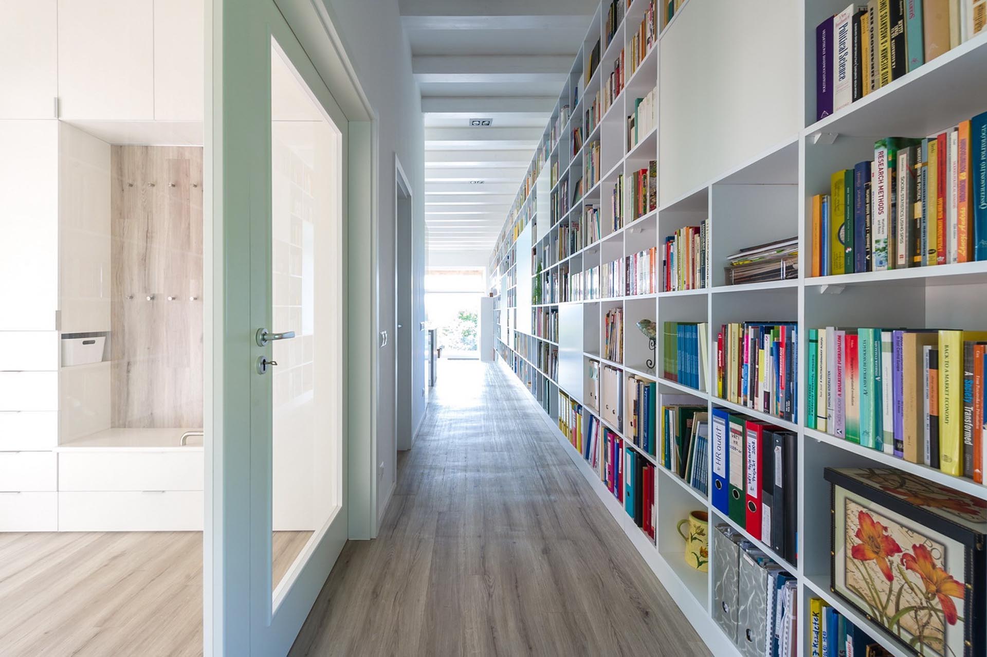 An entire wall is filled with bookshelves and includes window seats and a fireplace.