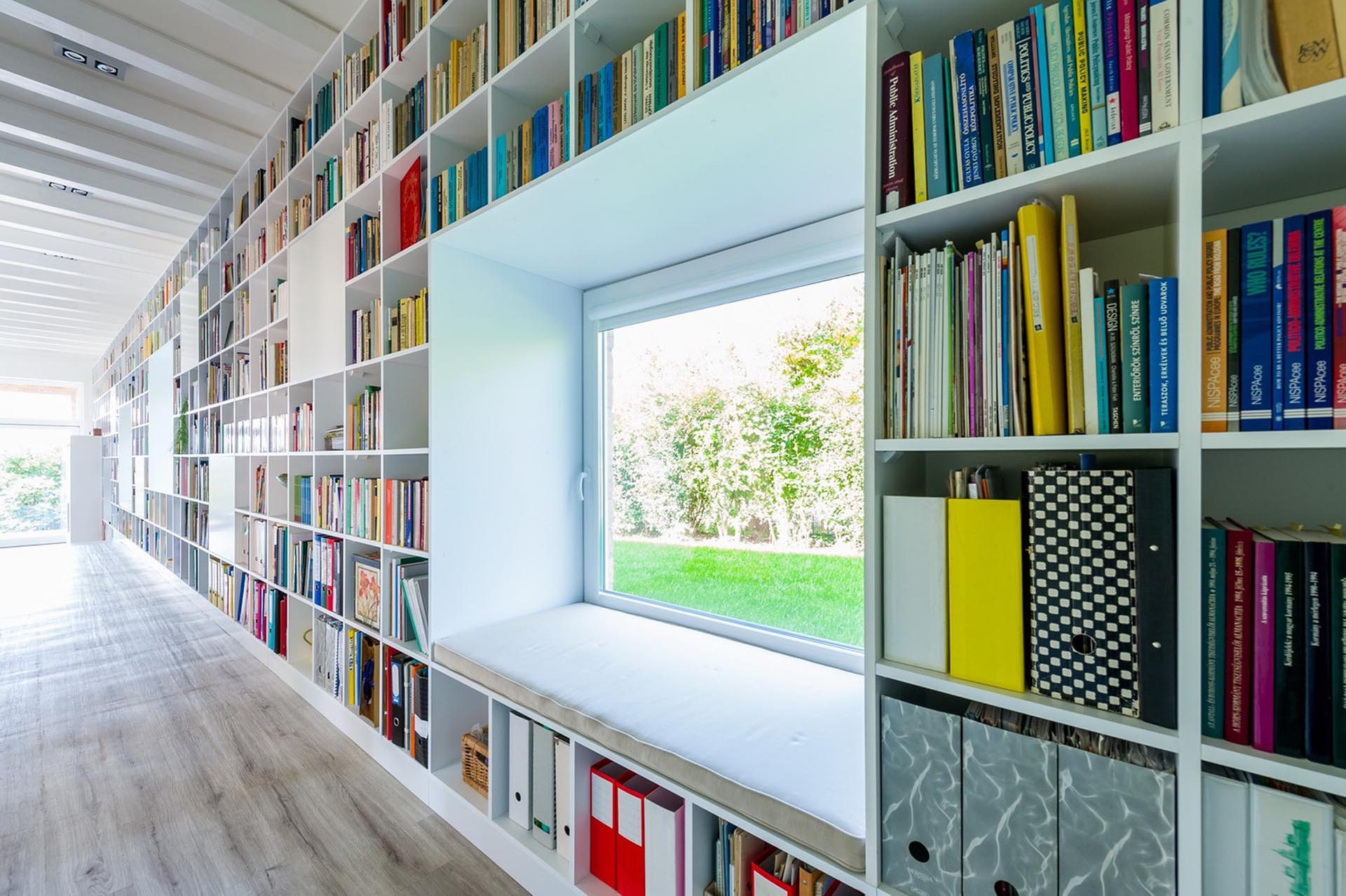 An entire wall is filled with bookshelves and includes window seats.