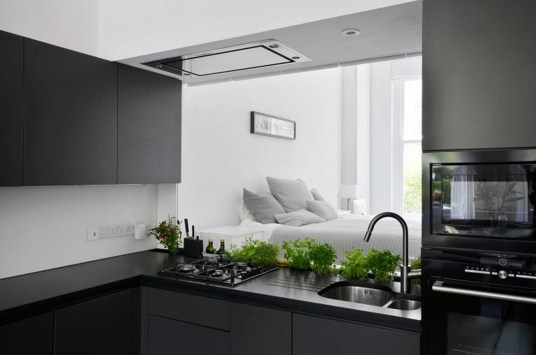 A Glass Backsplash In The Kitchen Lets Light Pass Through This Small Apartment