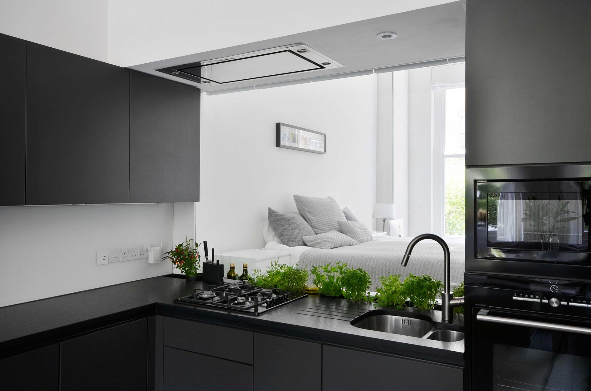 A glass backsplash in the kitchen provides views of the bedroom.