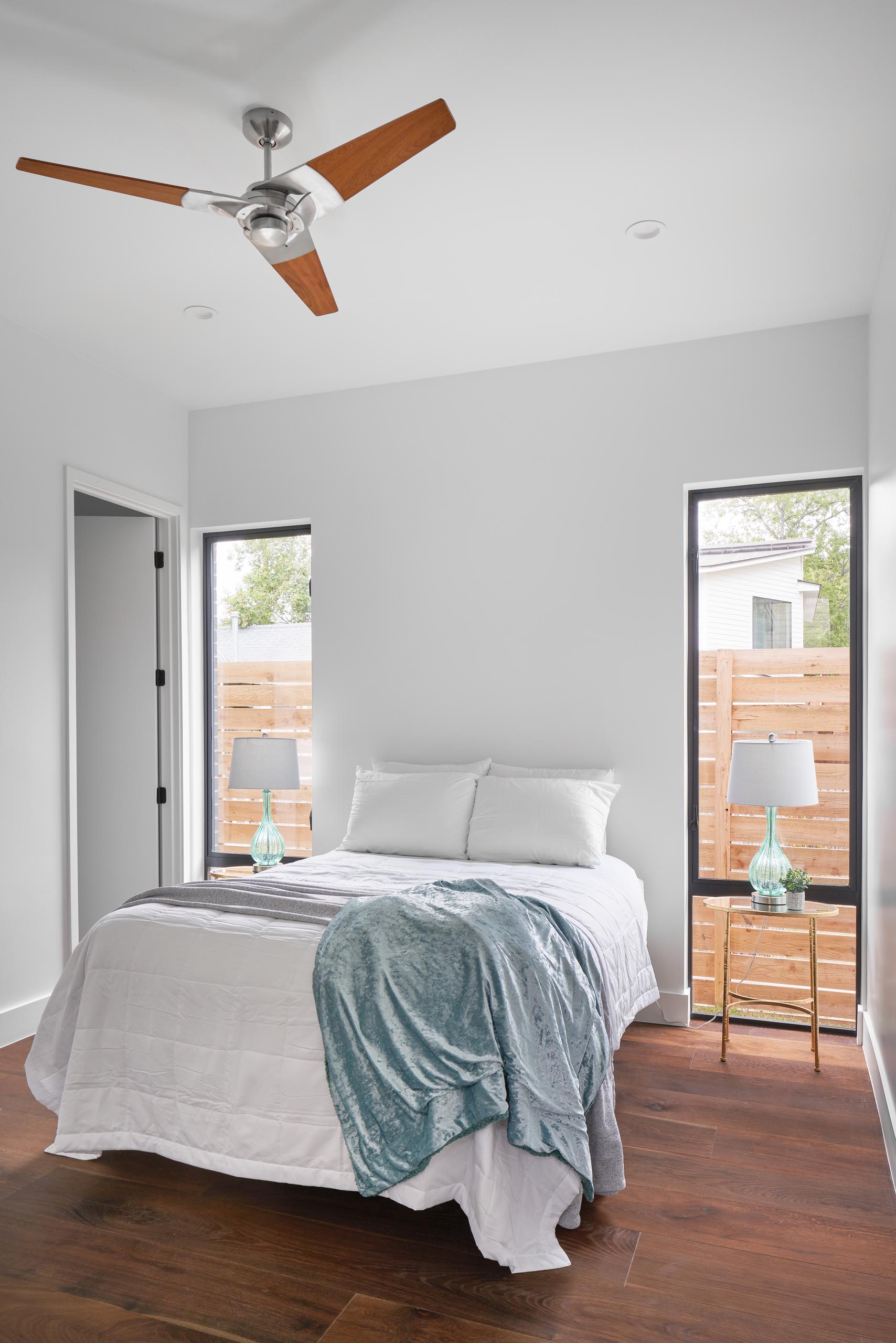 A simple guest bedroom idea, with side tables positioned in front of tall windows.