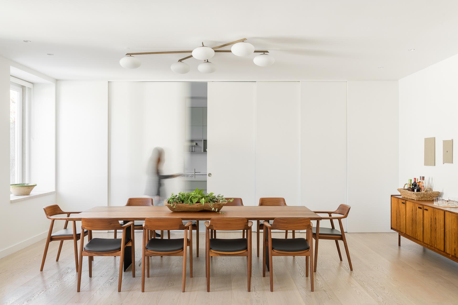 A kitchen is hidden from the dining room by sliding white panel doors.