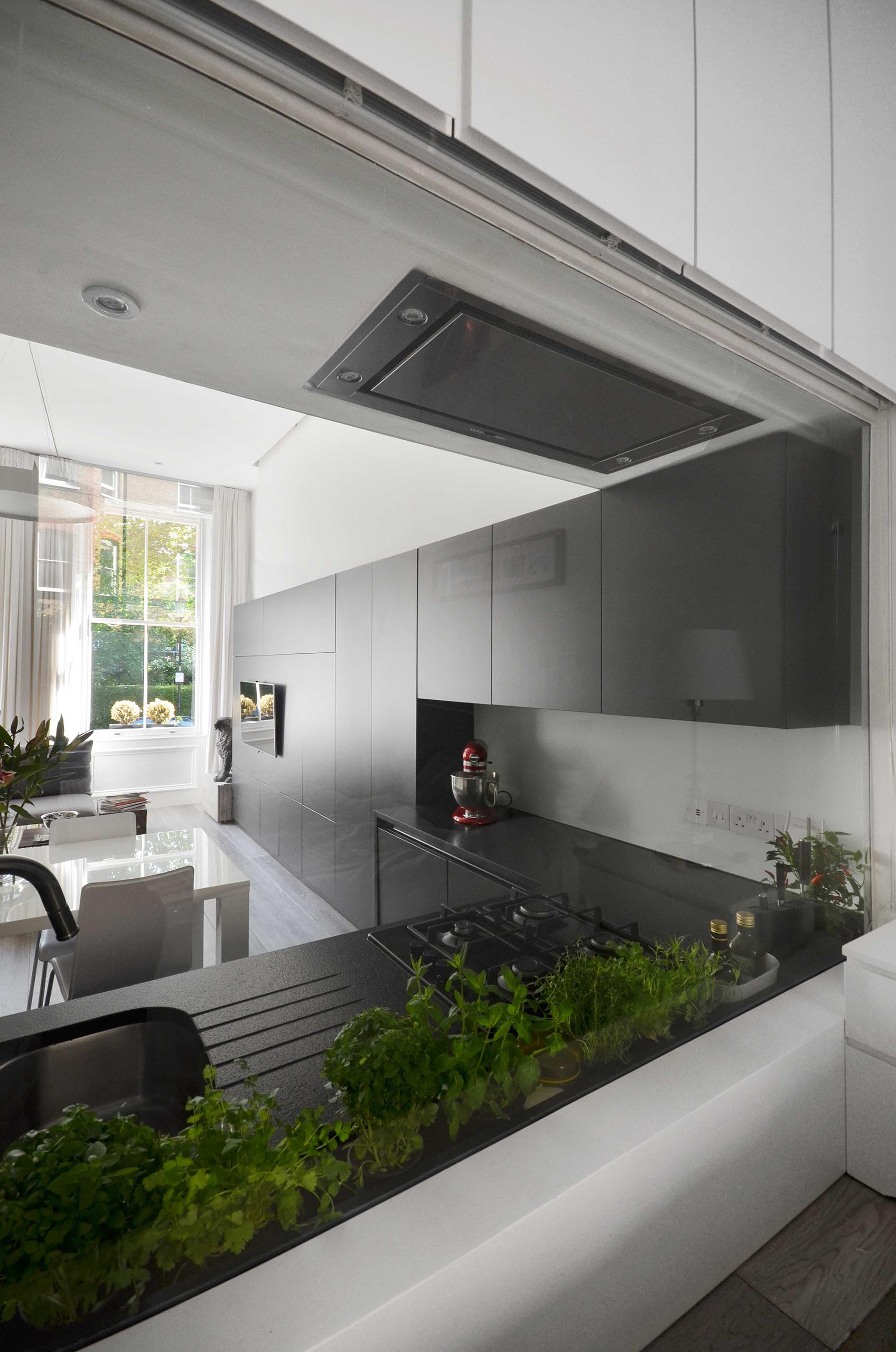 A window that doubles as a backsplash acts as a wall between the matte black kitchen and the bedroom.