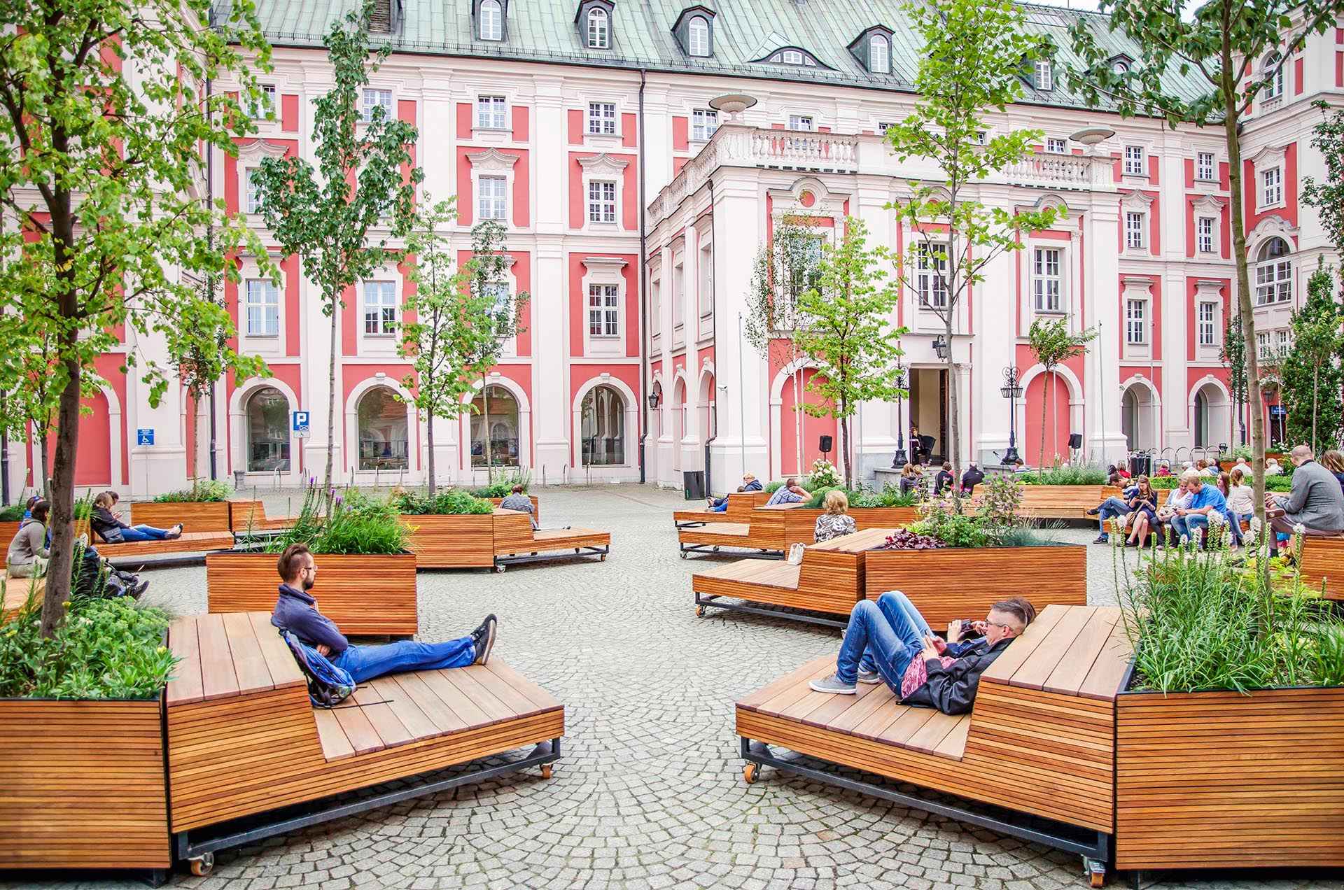 A courtyard filled with triangular wood planters and matching mobile benches.