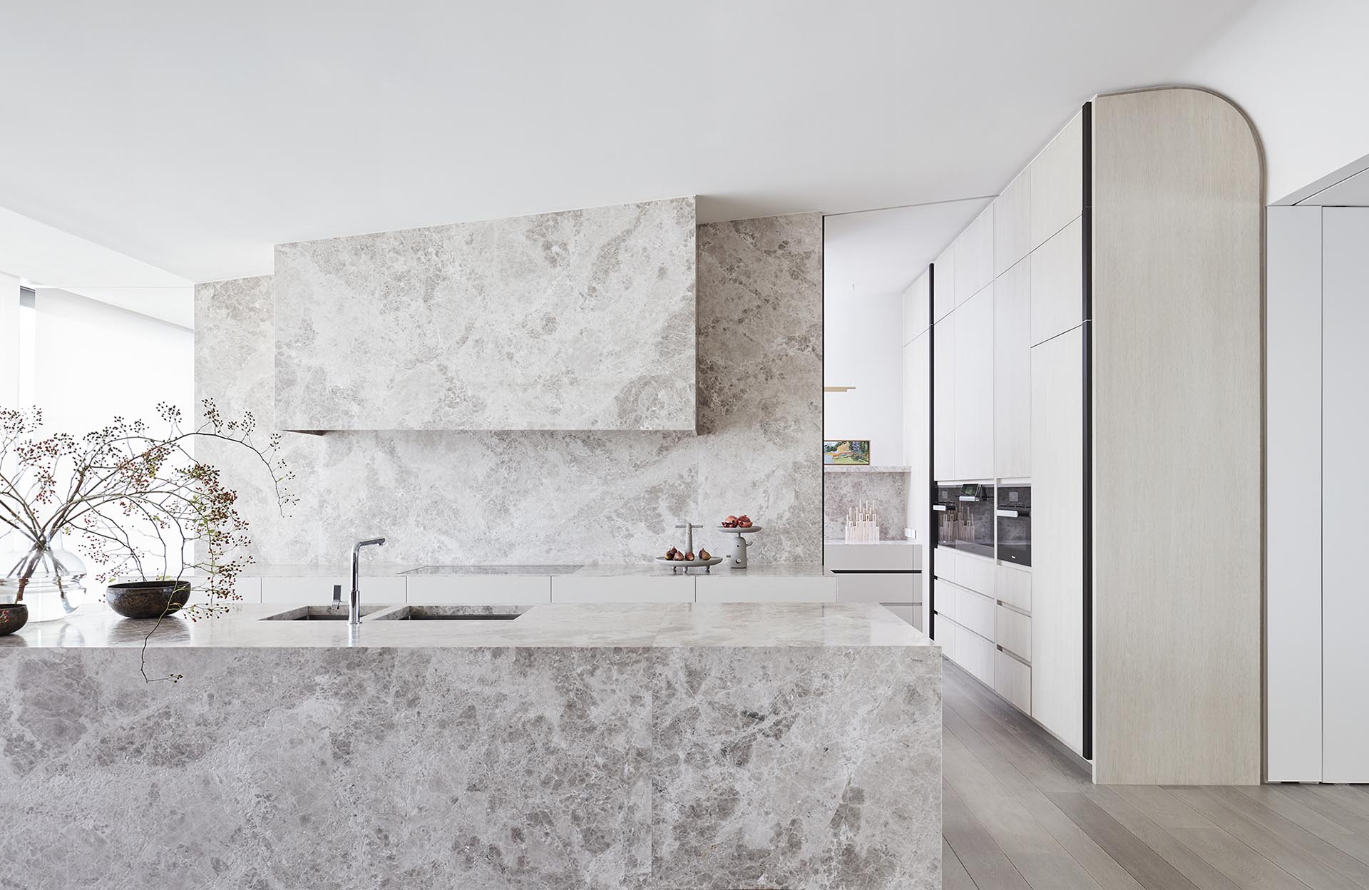 Limestone has been used in this modern kitchen to cover the island, and act as the backsplash that travels up to the angled ceiling.