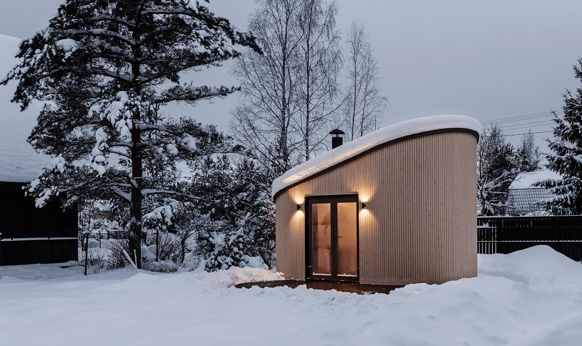 A small module pod with a curved wood exterior that can be used as an office pod, guest house, tiny house, or backyard BBQ house.