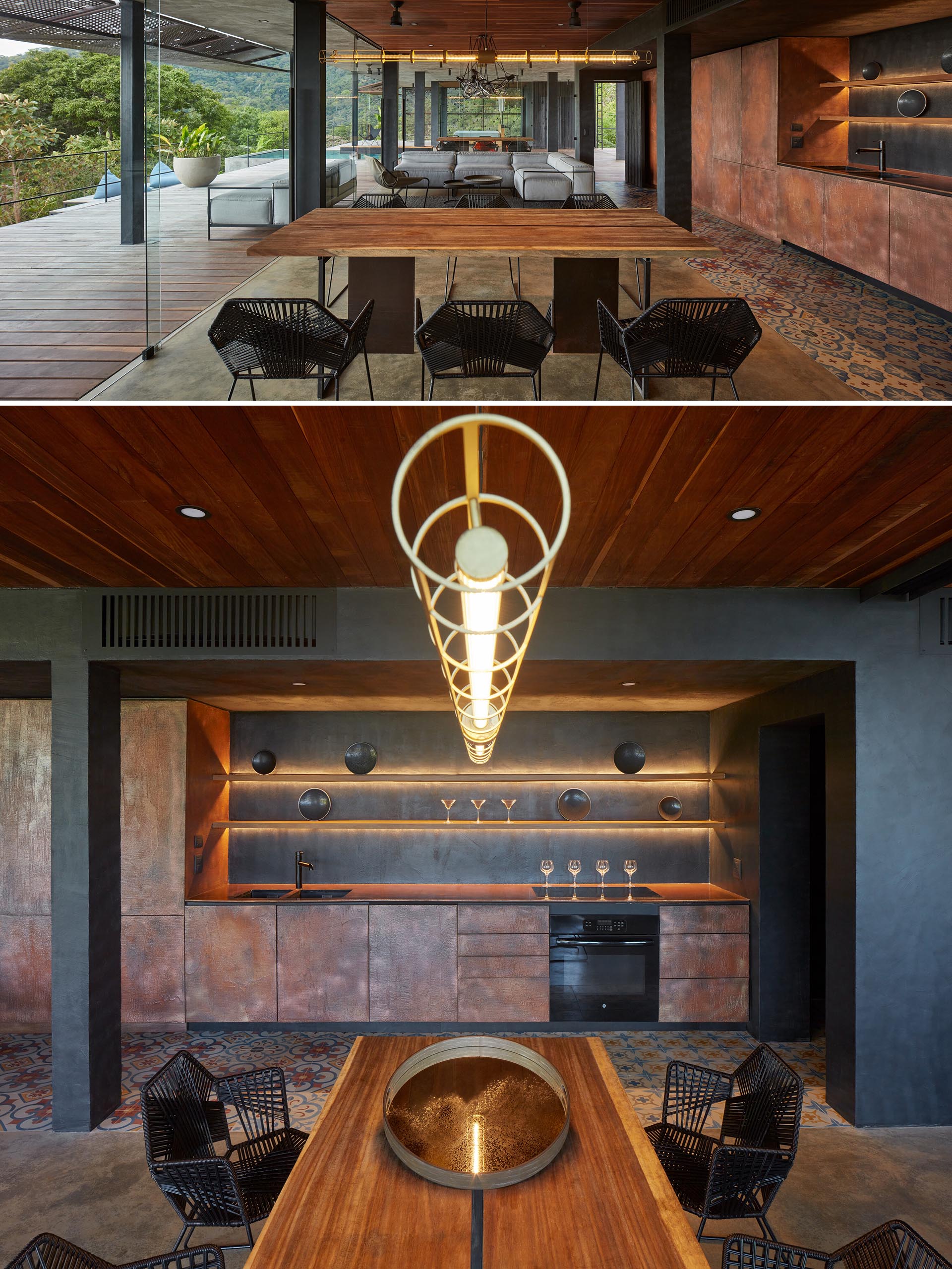 A wood dining table shares an open floor plan with a corten steel kitchen that has backlit shelving.