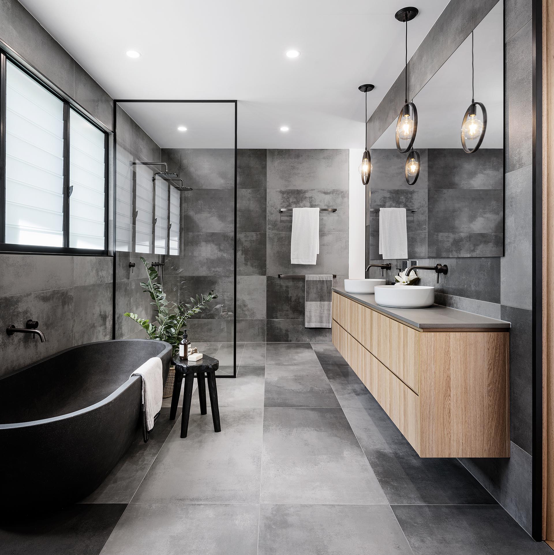 A modern master bathroom with a grey color palette, a freestanding bathtub, and a shower for two.