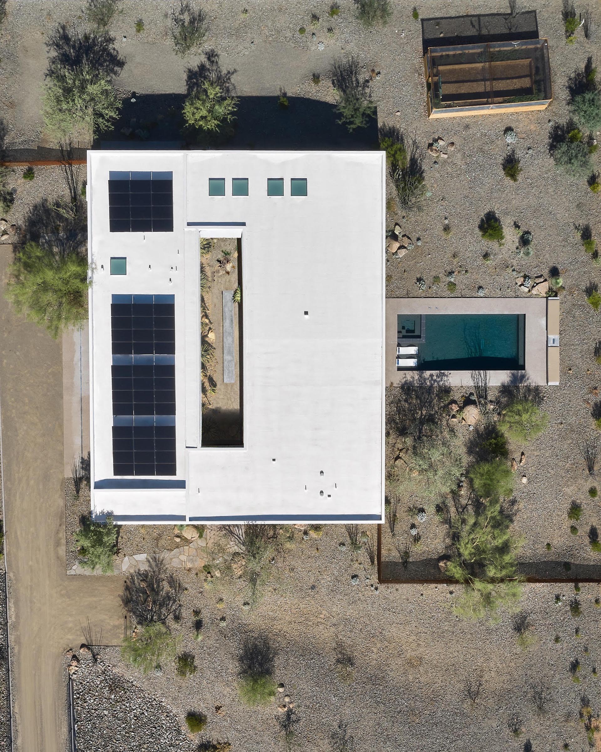 A modern house in the desert with a central courtyard, a swimming pool, and solar on the roof.