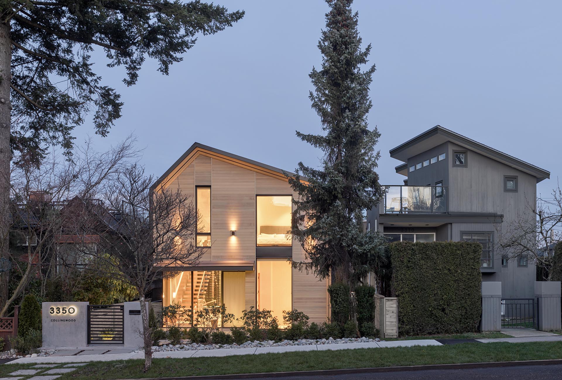 A modern house with a wood facade that's lit up with exterior lighting.