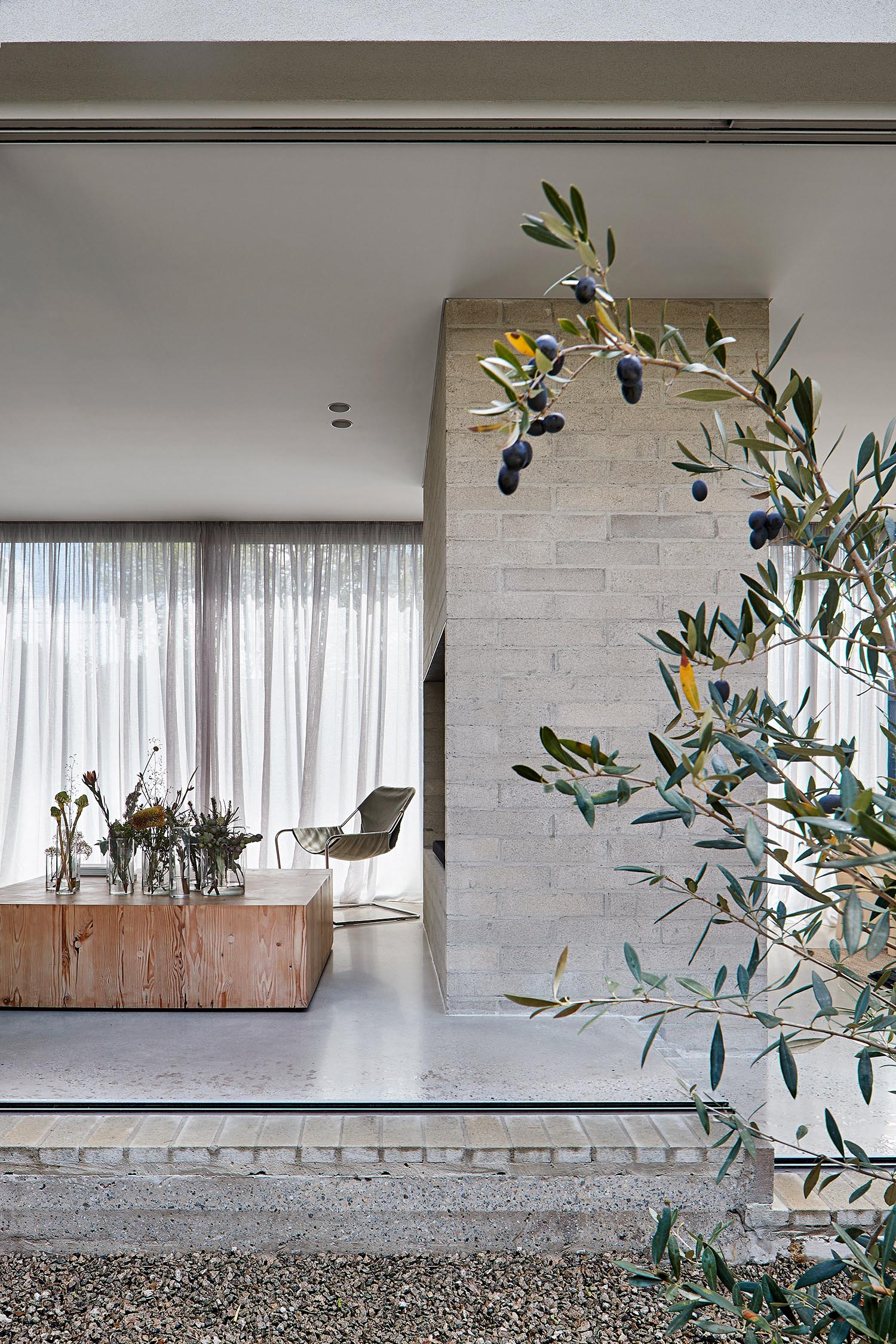 A modern living room with wood block coffee table, light colored brick, and concrete floor.