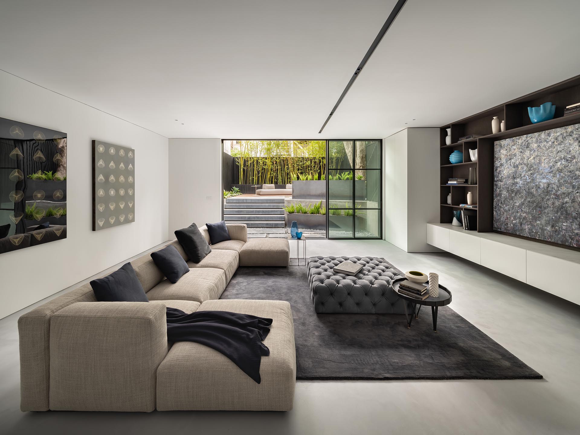 A living room with a glass wall opens to the terraced garden.