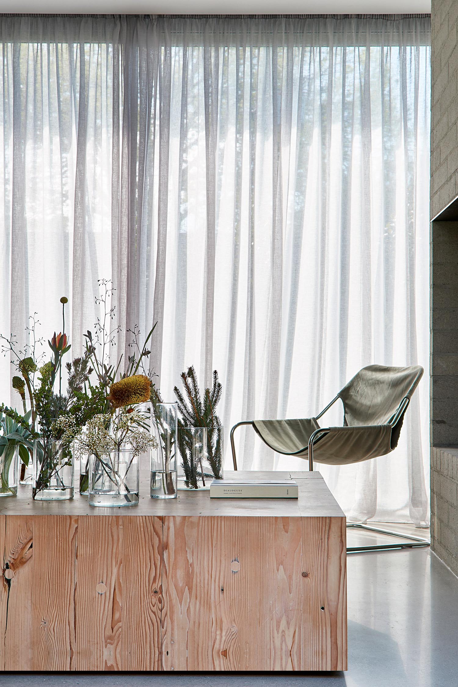 Modern living room with flowing curtains and wood block coffee table.