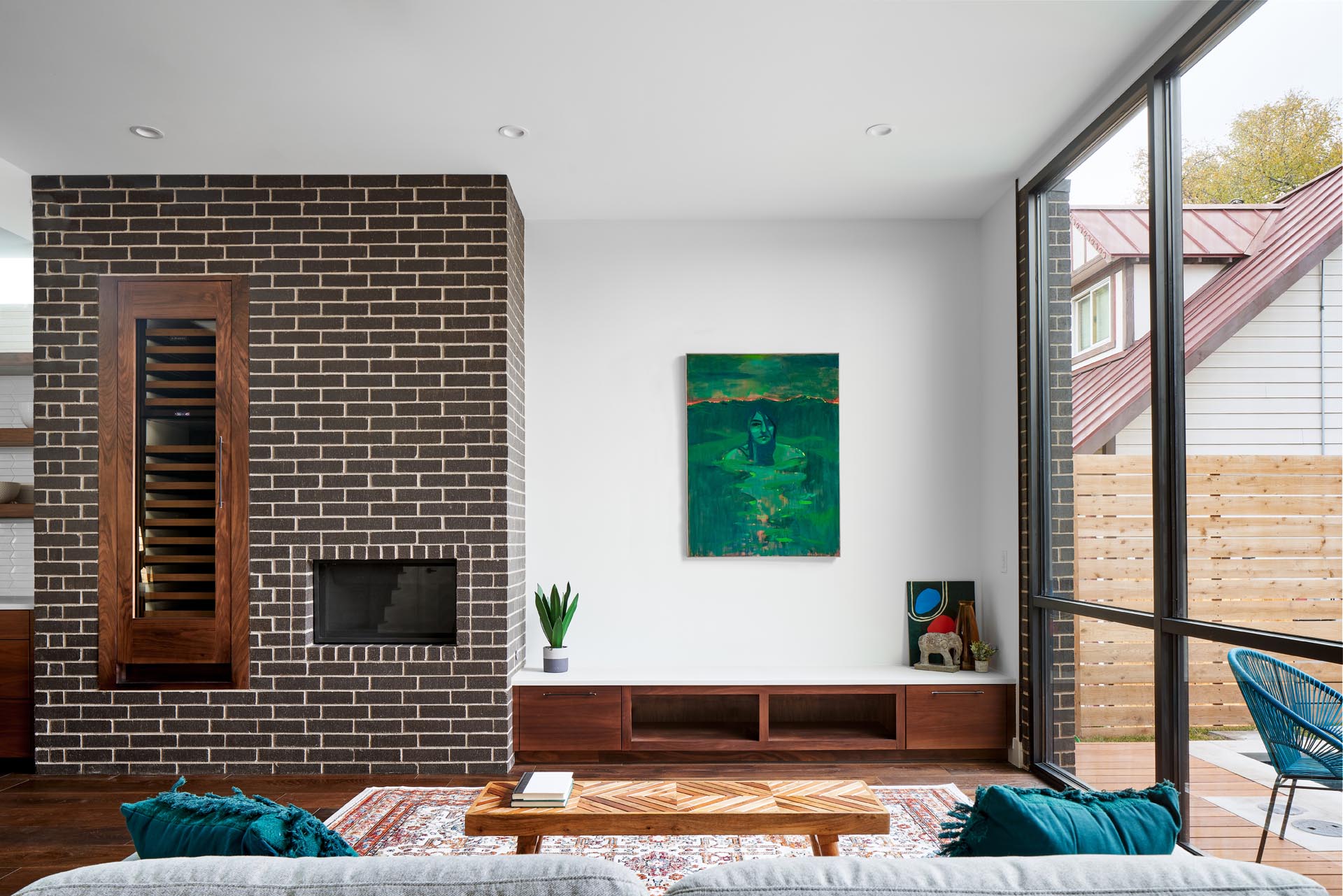 A modern living room with a brick accent, fireplace, and custom wood cabinetry.