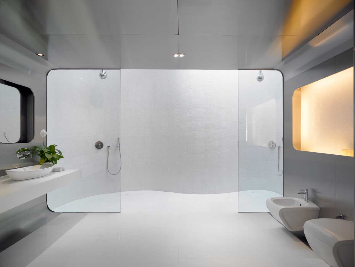 A modern bathroom with stainless steel walls, glass shower screens, and dual showers with a skylight.