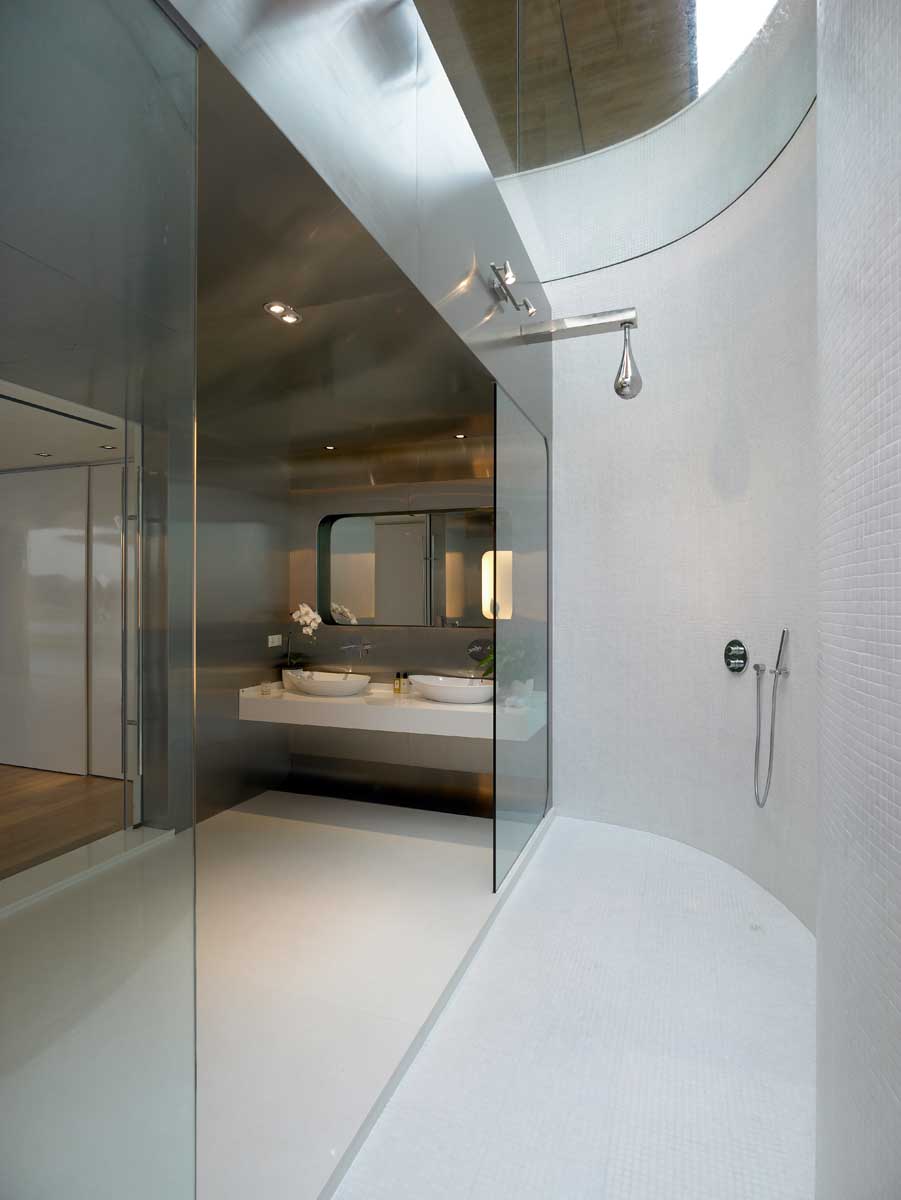 A modern bathroom with stainless steel walls and dual showers with a skylight.