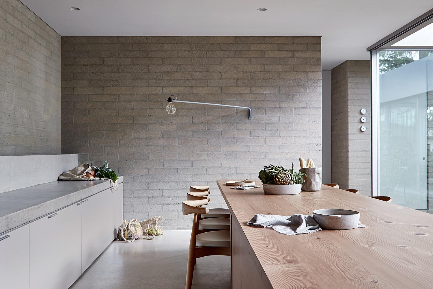 Long wood kitchen island with dining table incorporated.