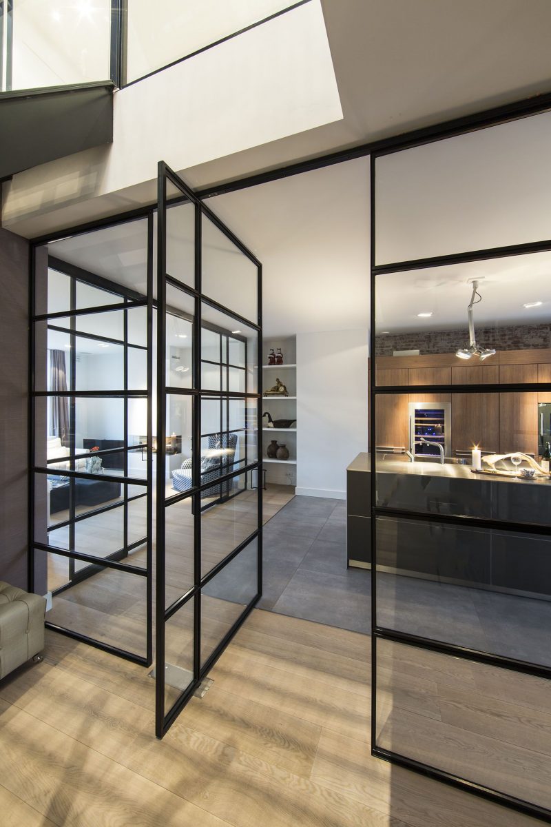 A black framed pivoting glass door and walls.