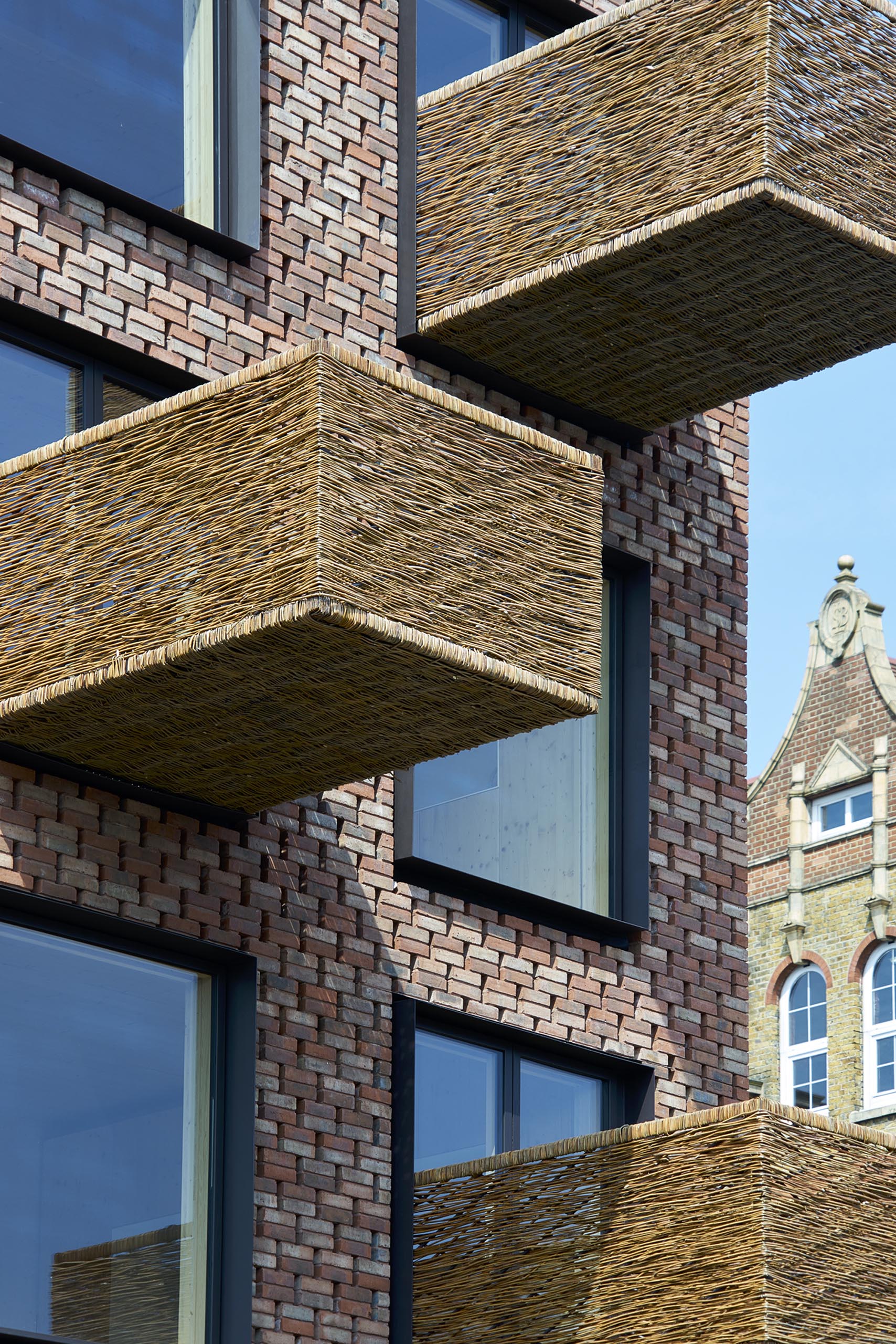 Woven wicker balconies protrude from a brick apartment building.