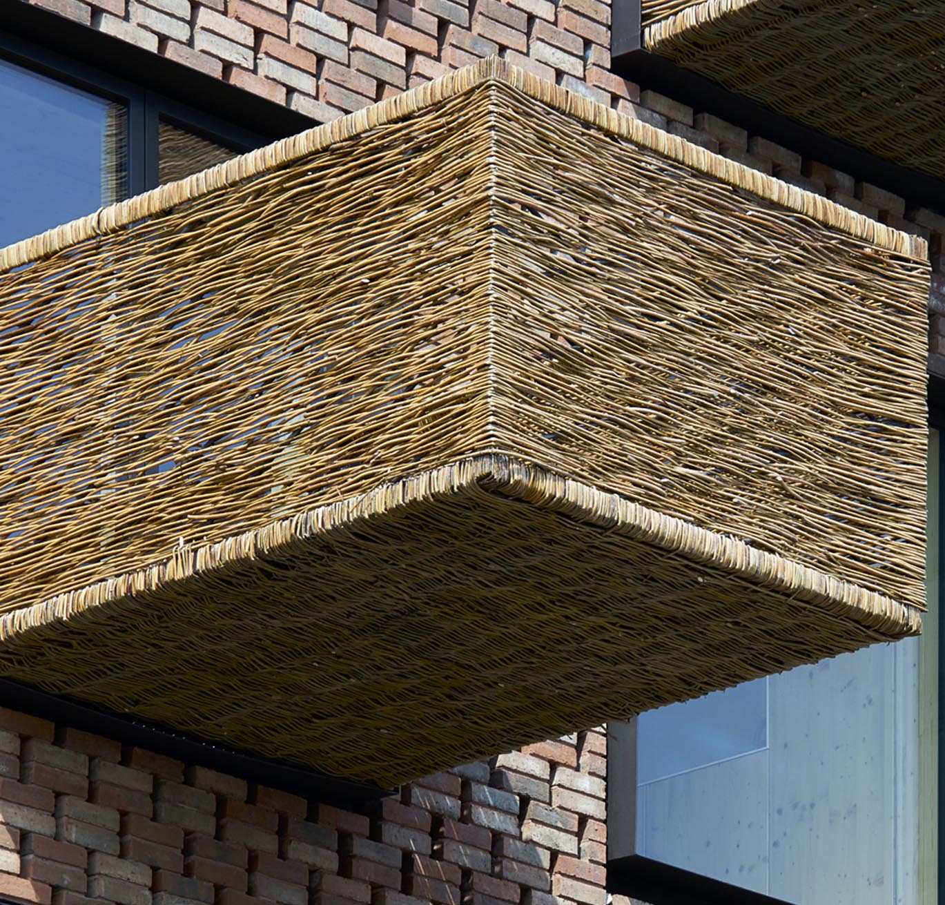 A protruding balcony made with a steel frame covered in woven wicker.