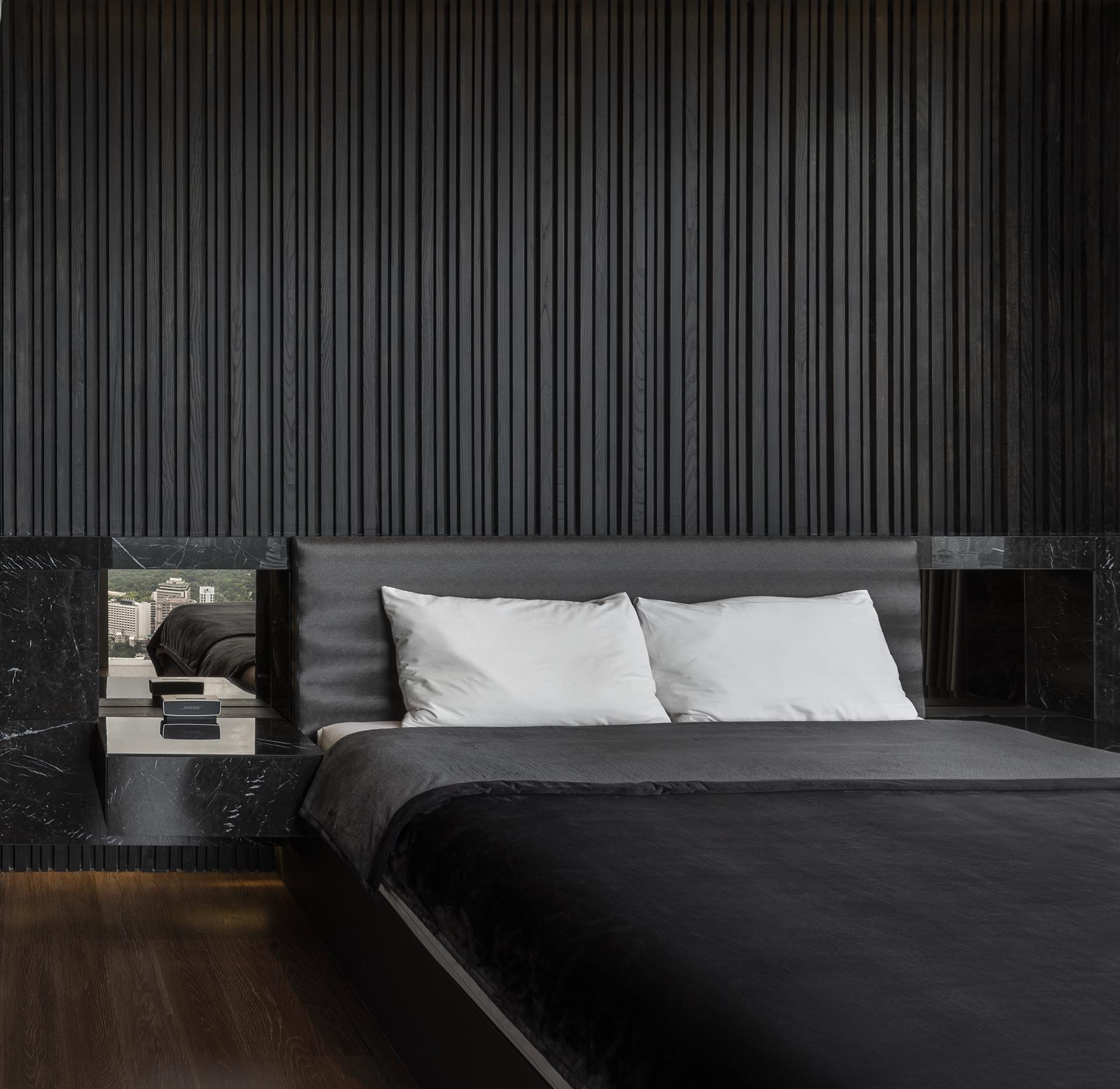 A modern black bedroom with a textured wood accent wall.