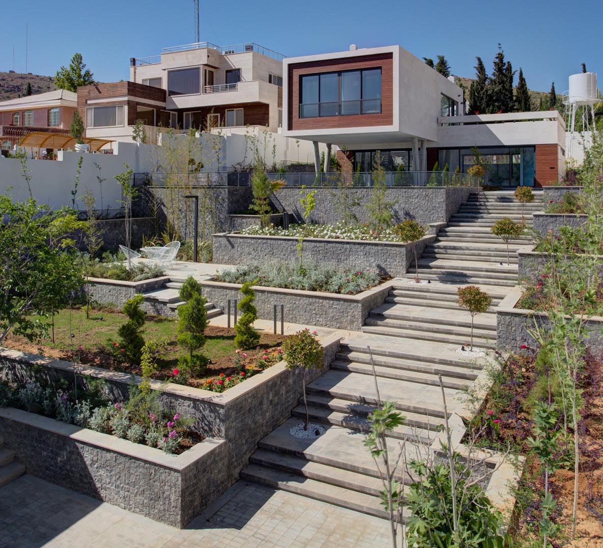 A terraced garden with wide stairs, sitting areas, and plenty of plants.