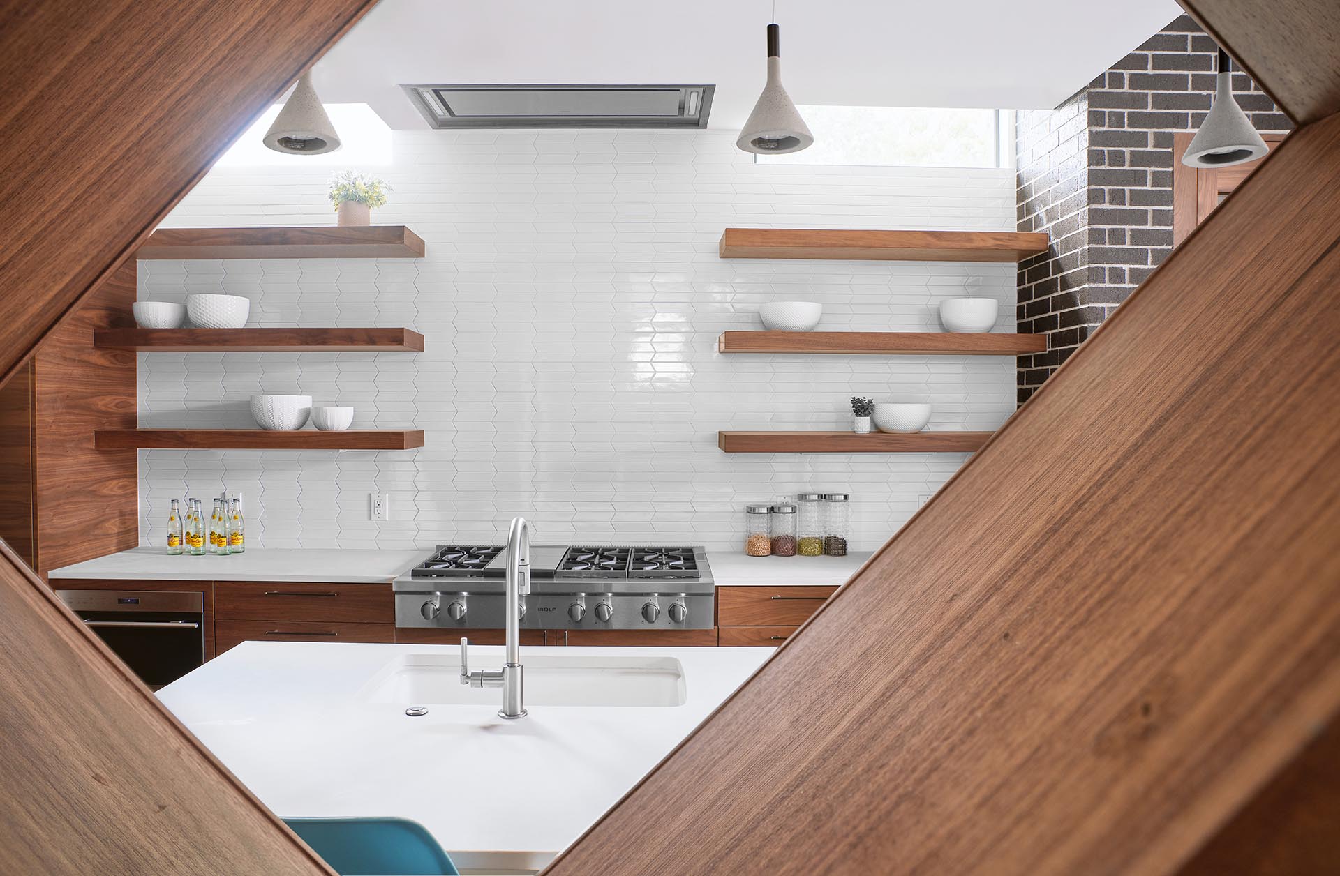 A open wood shelf provides a view of a modern kitchen.