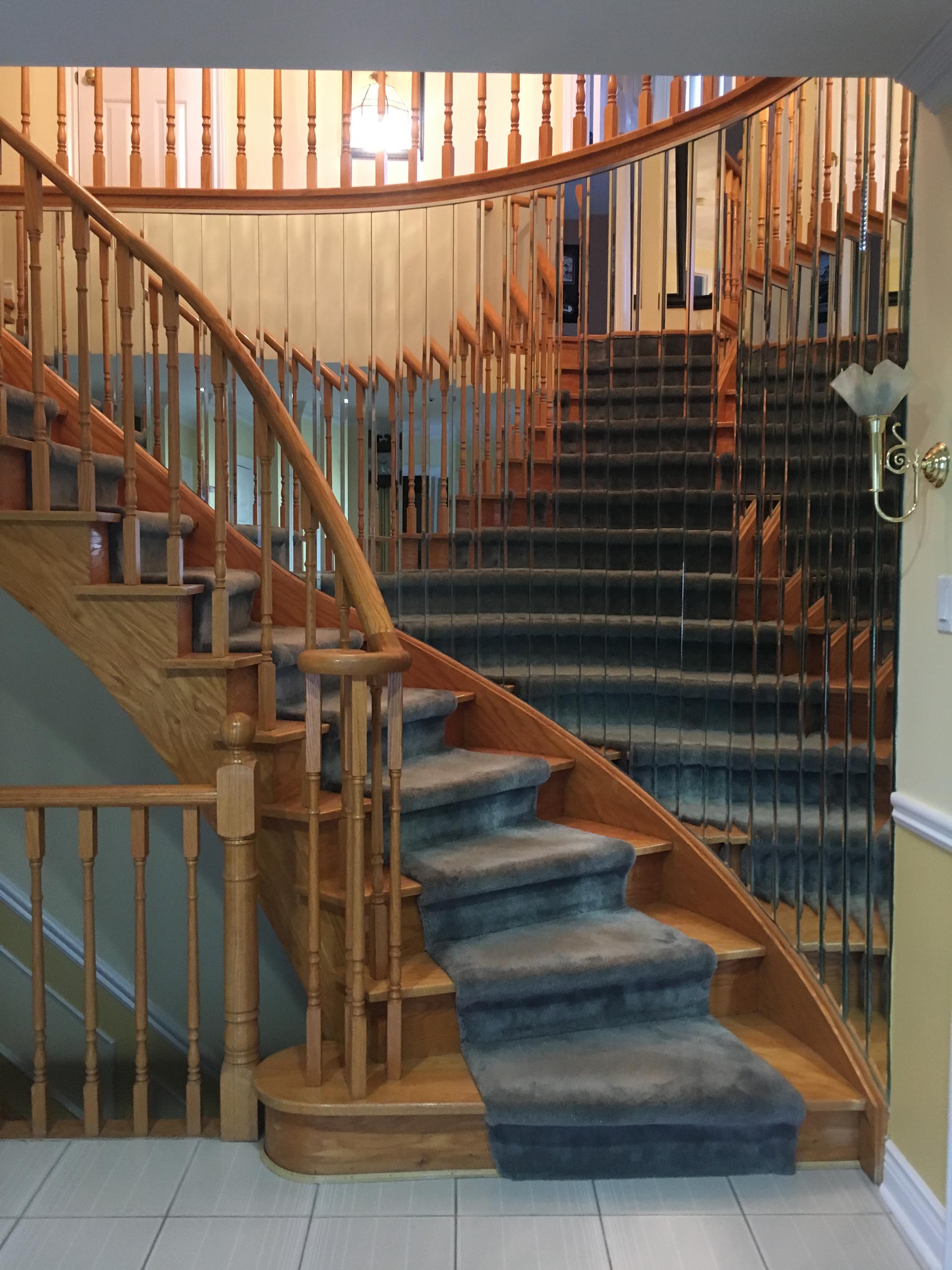 A 1970s staircase with a curved design and mirrored wall.