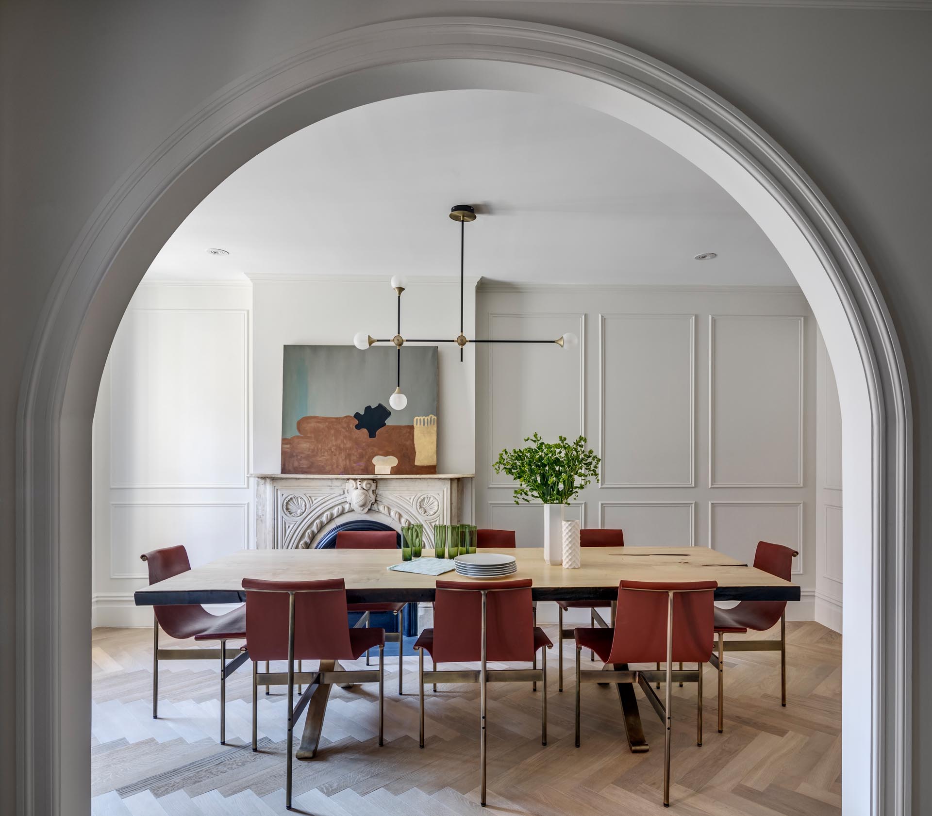 A dining room with a large wood table, an arched doorway, and a fireplace.