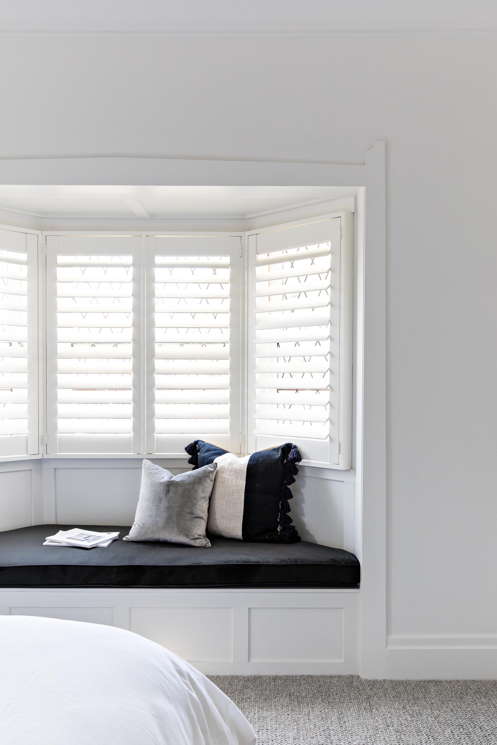 A bay window a custom designed window seat and black upholstered cushion.