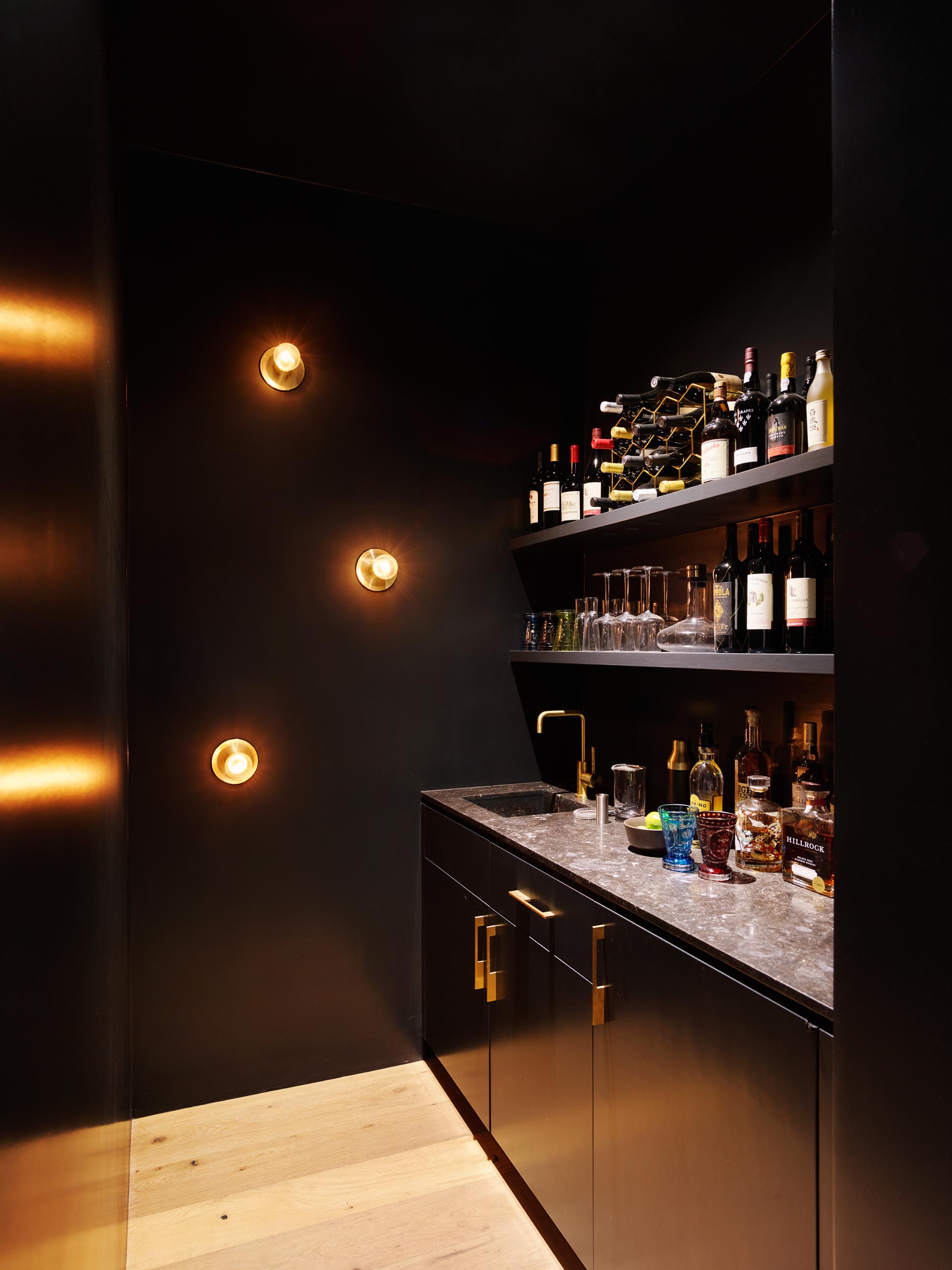 A small black home bar with shelving and cabinets.