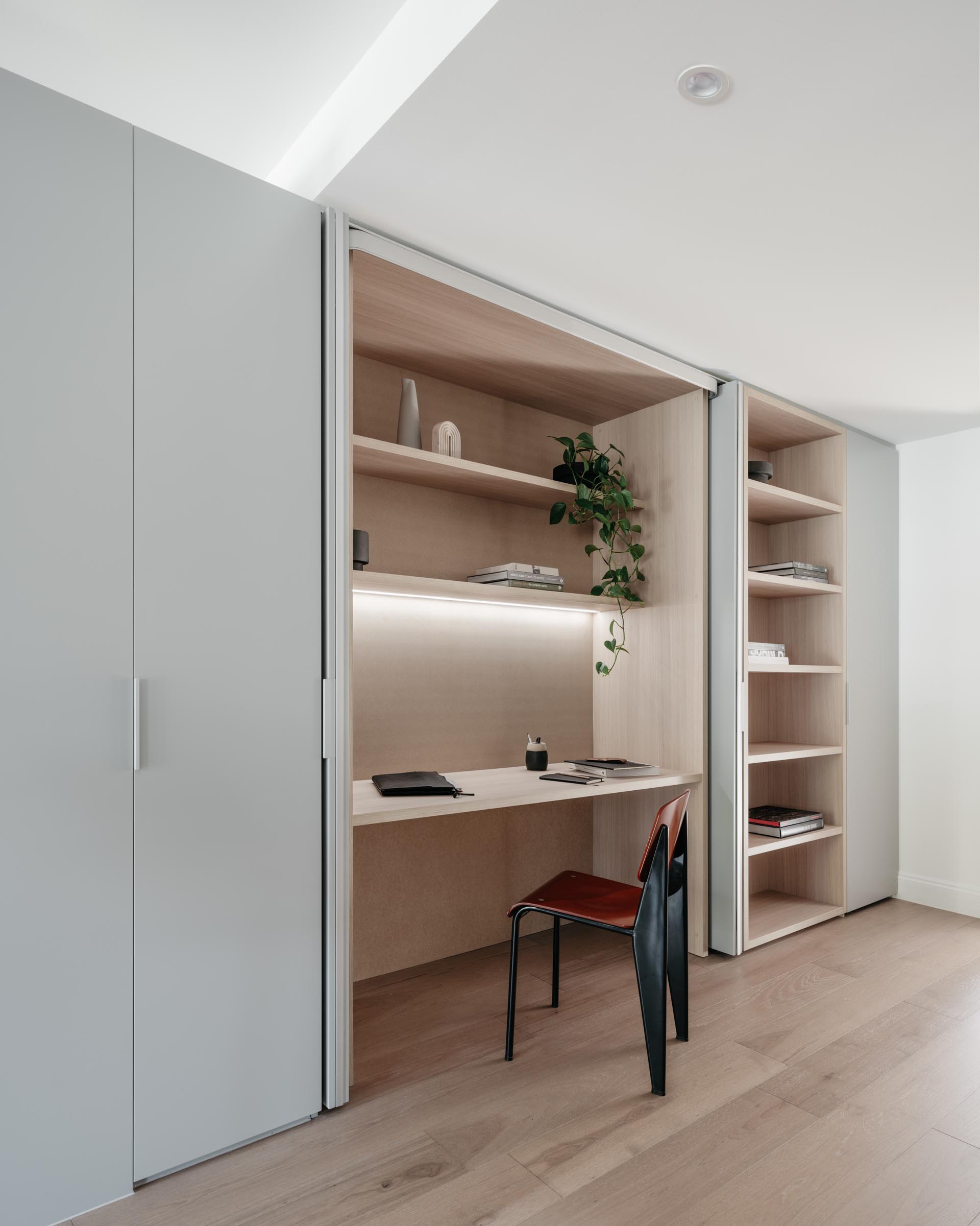 A modern wood-lined home office hidden within a closet.