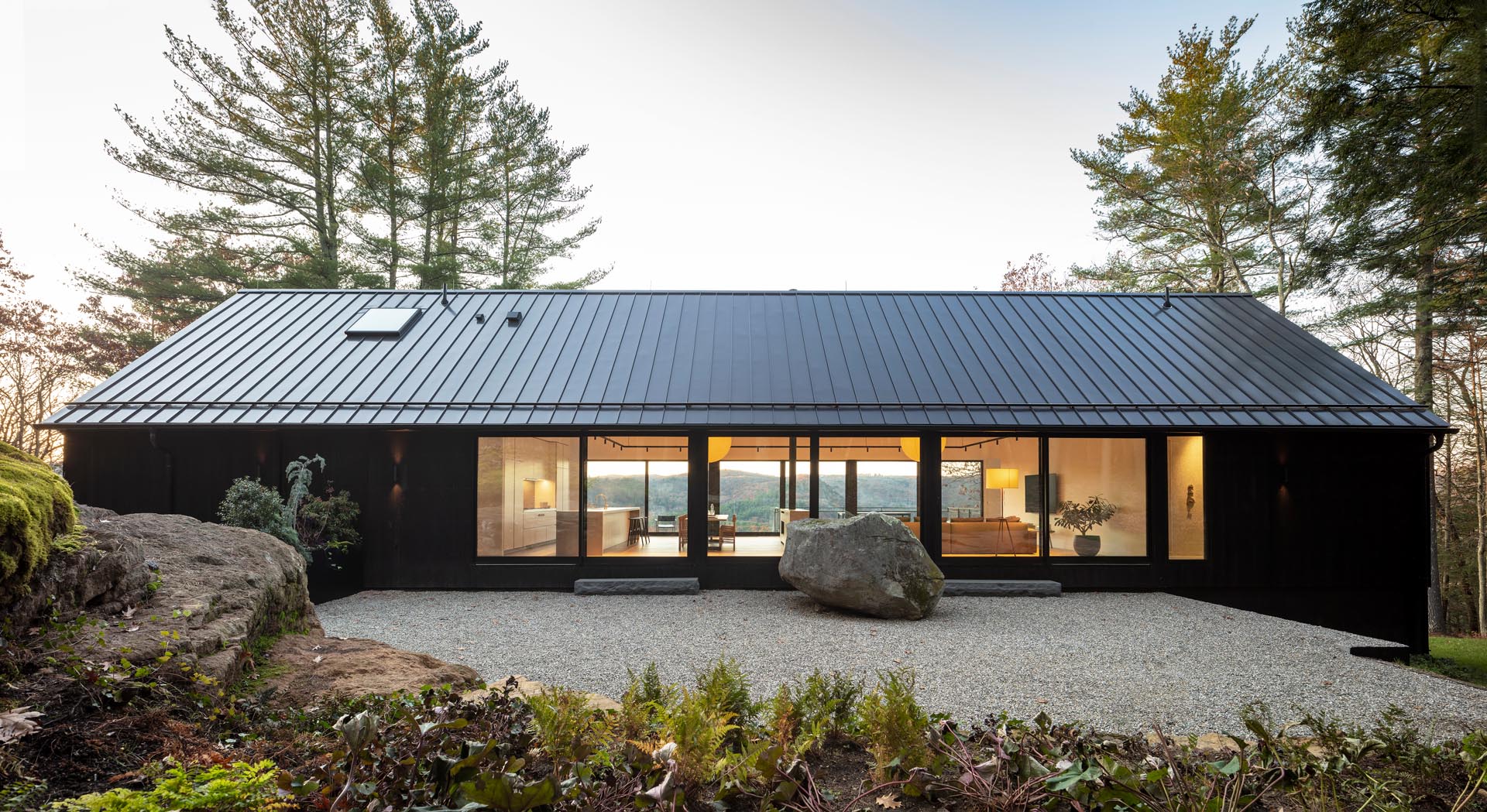 A modern black house with a black roof and Shou Sugi Ban exterior siding.