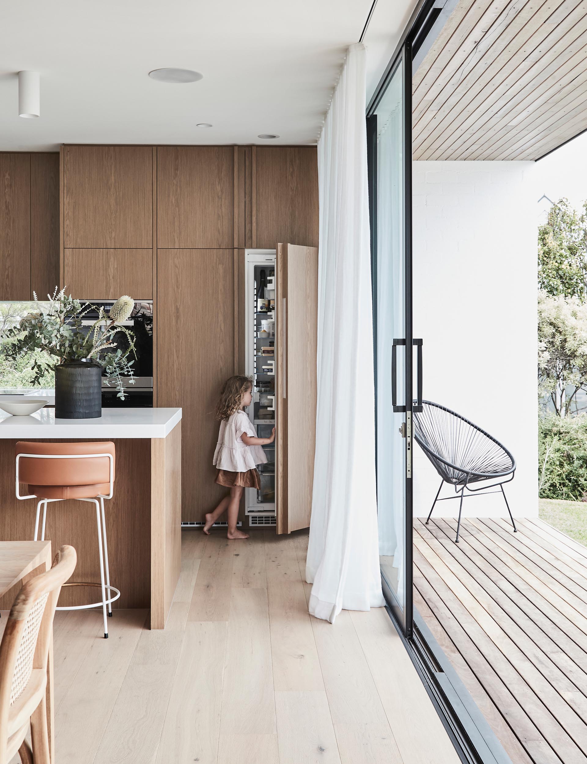 A modern wood kitchen with an integrated fridge.