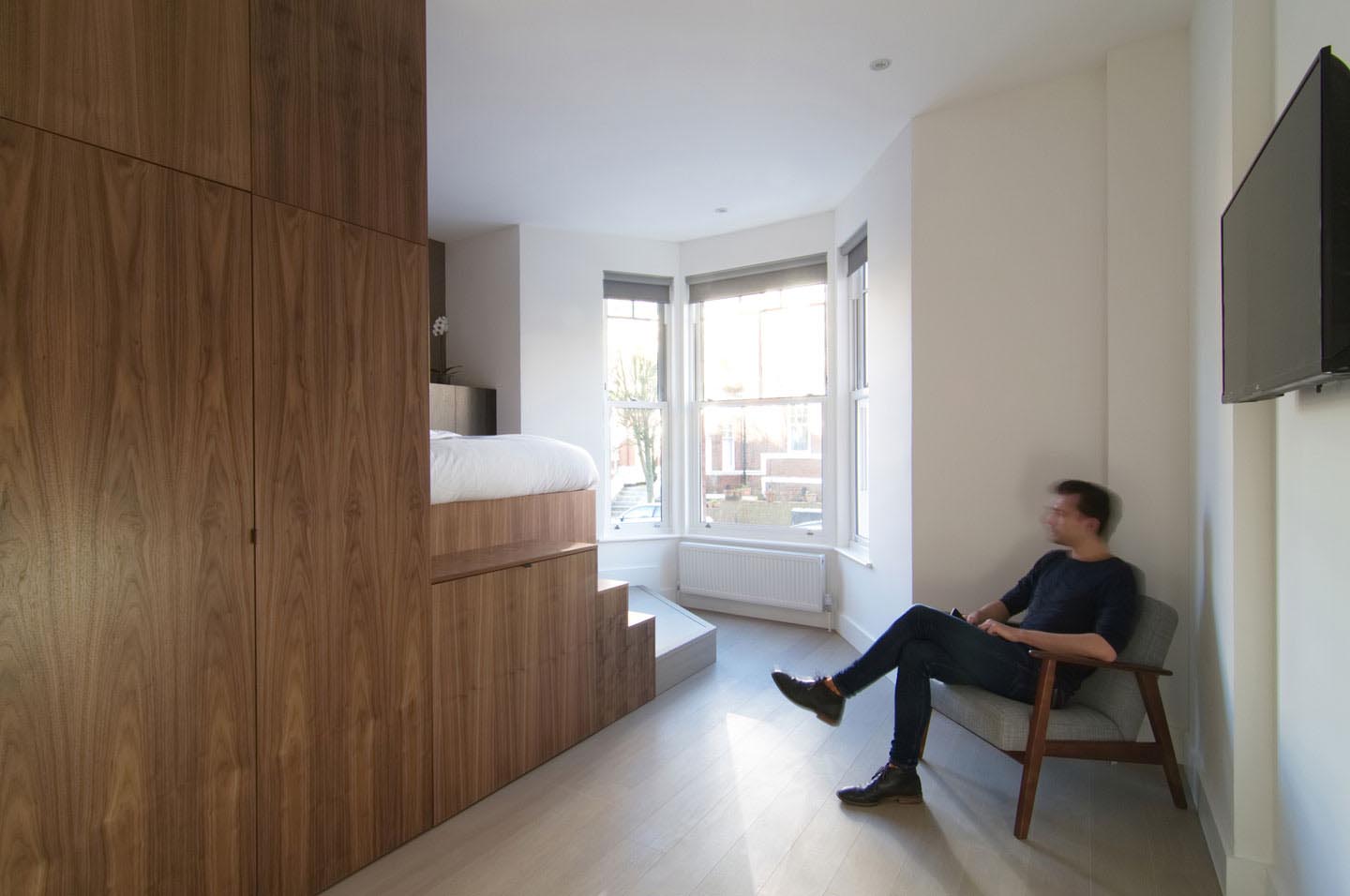 A micro apartment with a small kitchen, slide out desk, and loft bed.