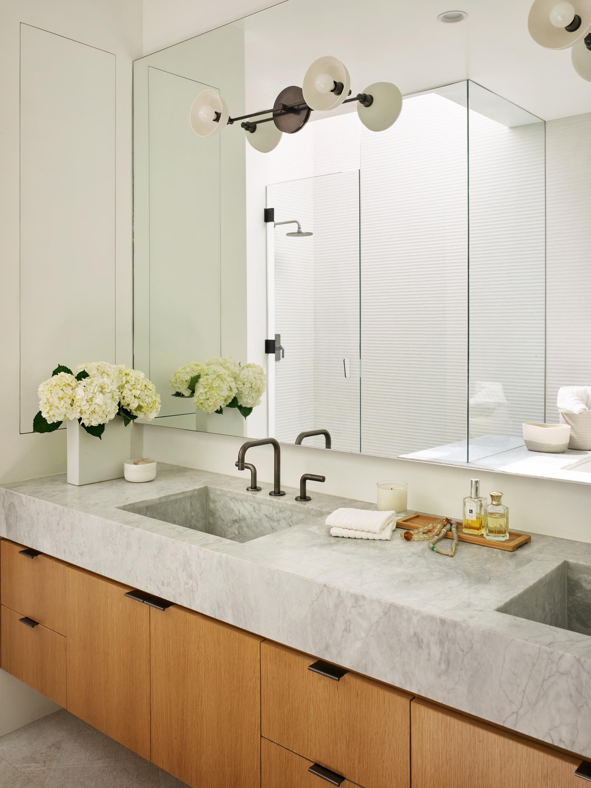 A master bathroom with a marble counter that has built-in sinks and sits on top of a wood vanity.