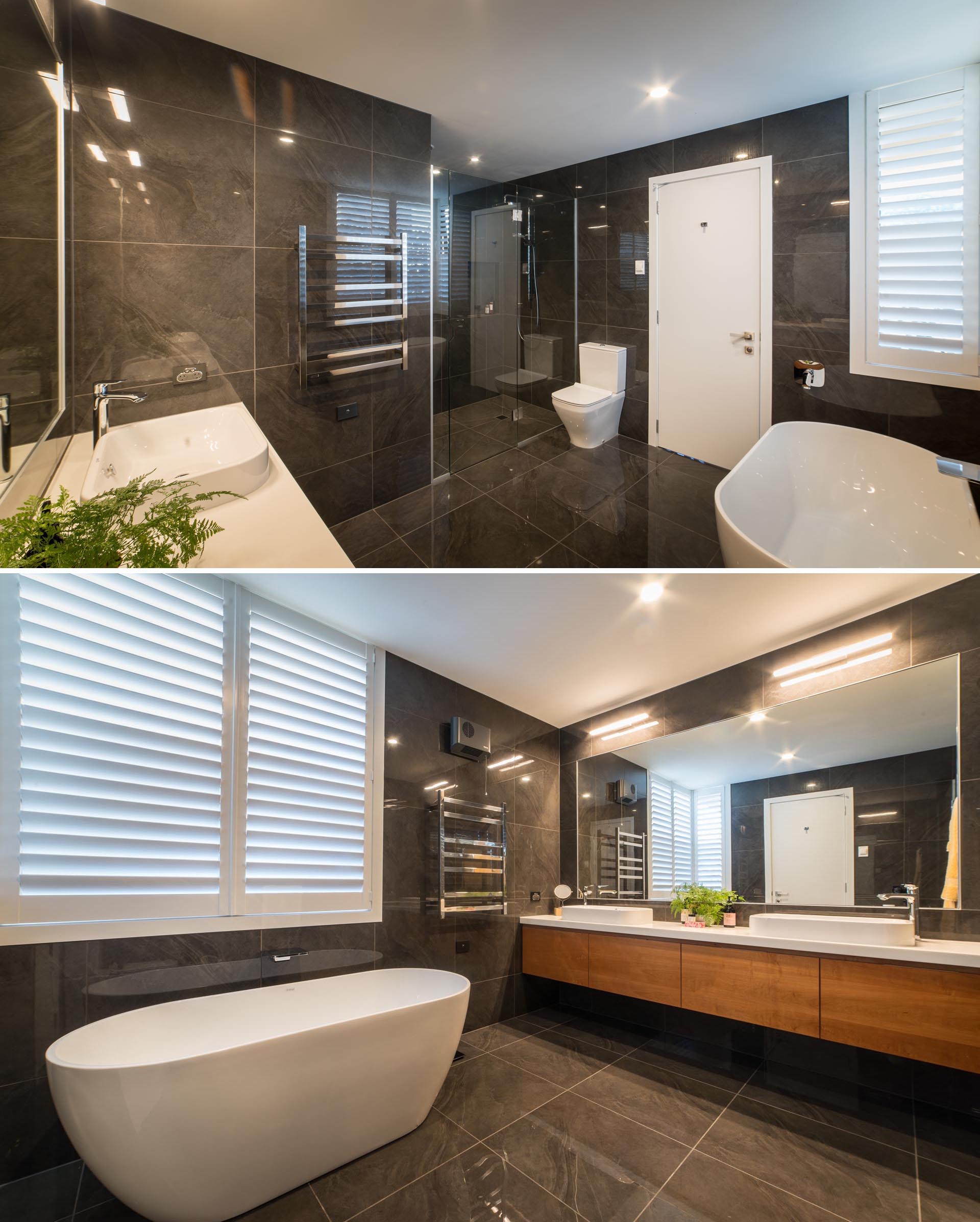 A modern master bathroom with large format dark colored tiles that cover the walls and floor, and a white freestanding bathtub and countertop that provide a contrasting element.