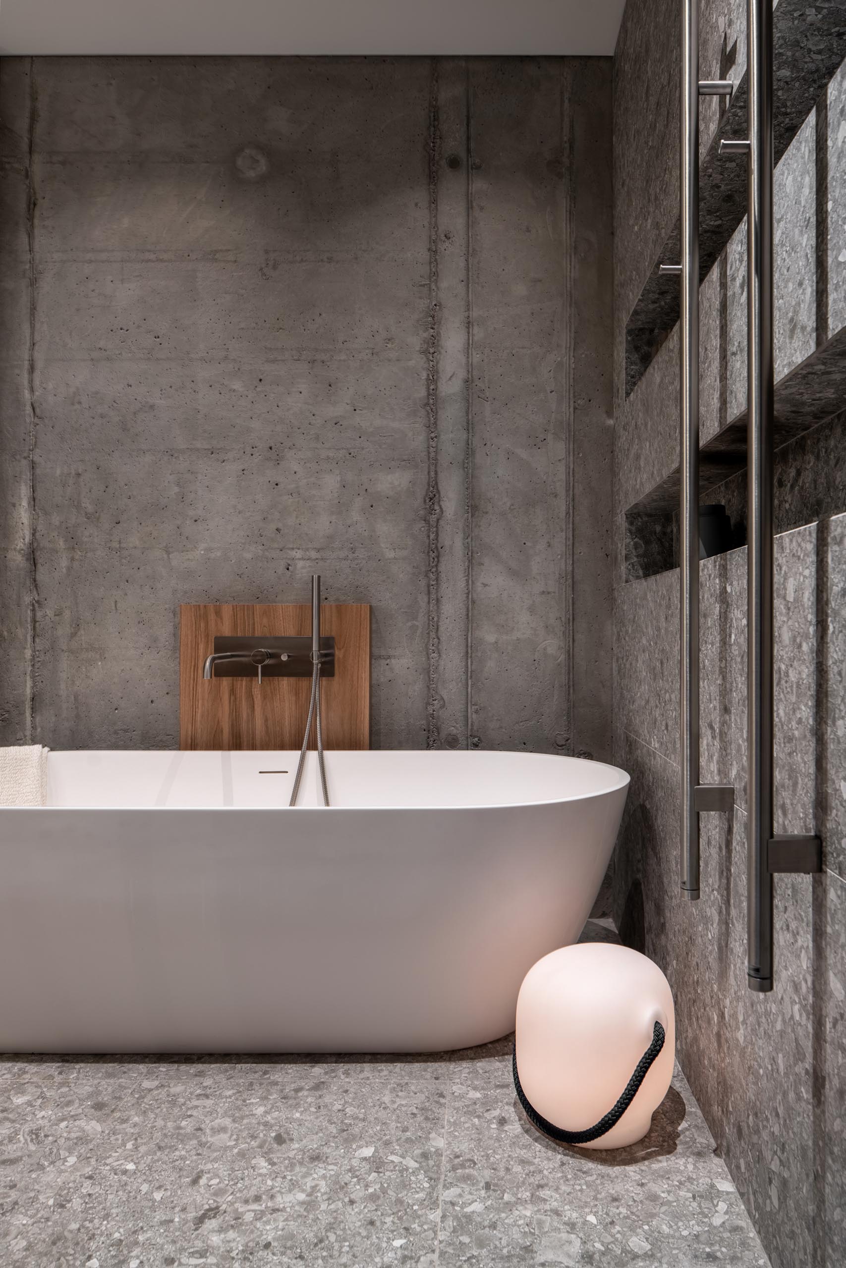 A modern bathroom with a freestanding white bathtub and a shower with built-in shelving niches.