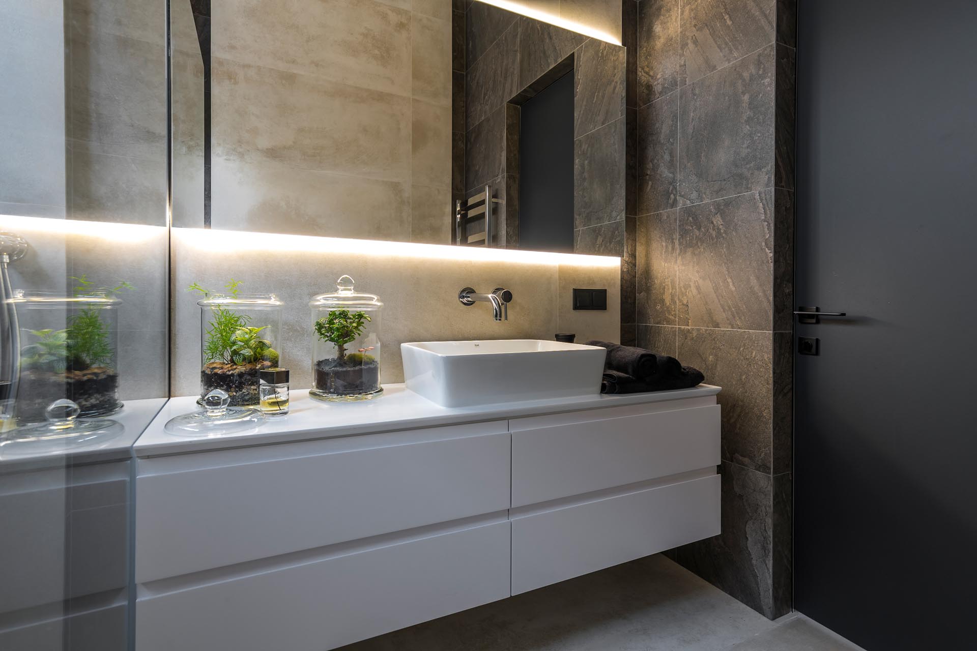 A modern bathroom with a white vanity and a backlit mirror.