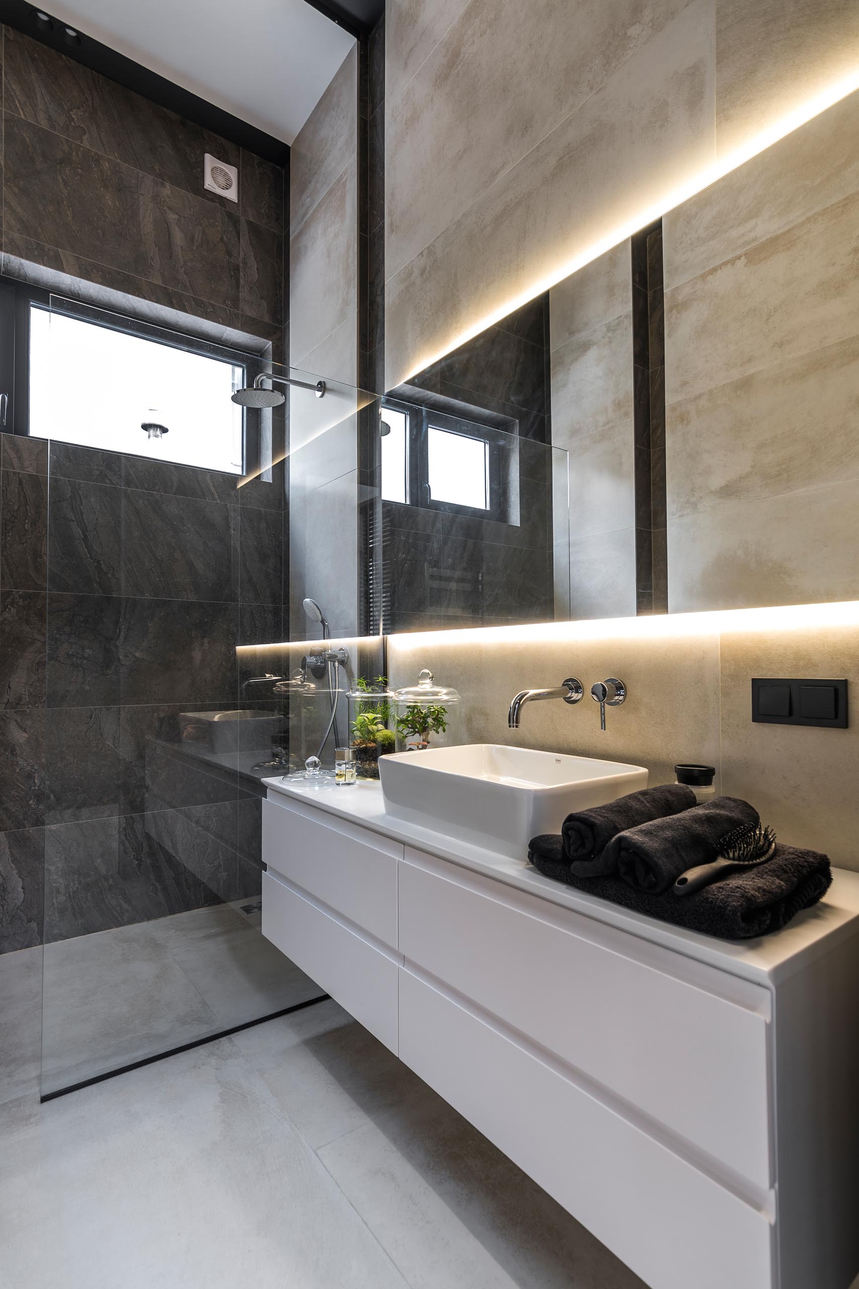 A modern bathroom with a white vanity and a backlit mirror.