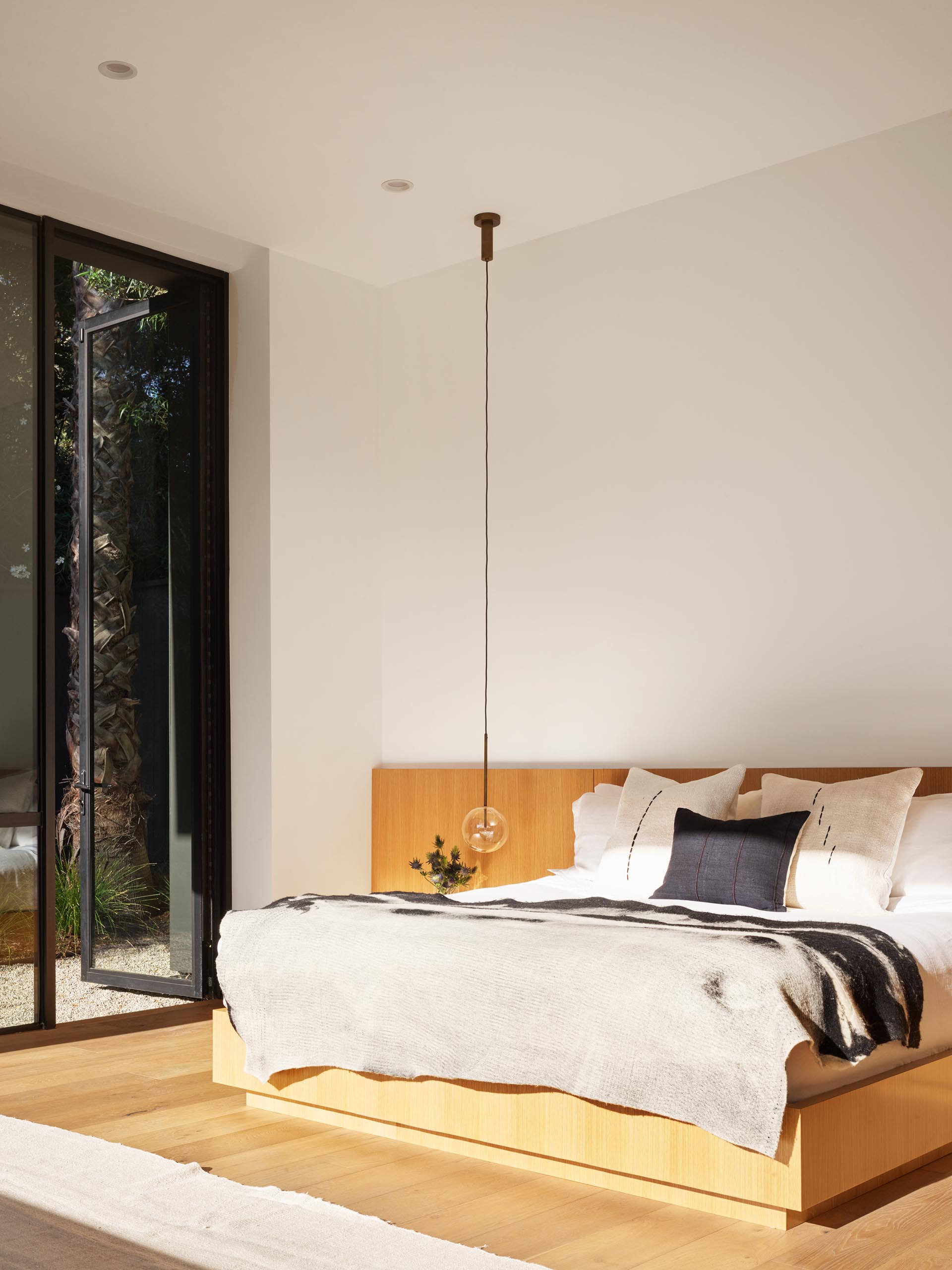 A modern bedroom with a pendant light that acts as a bedside lamp.