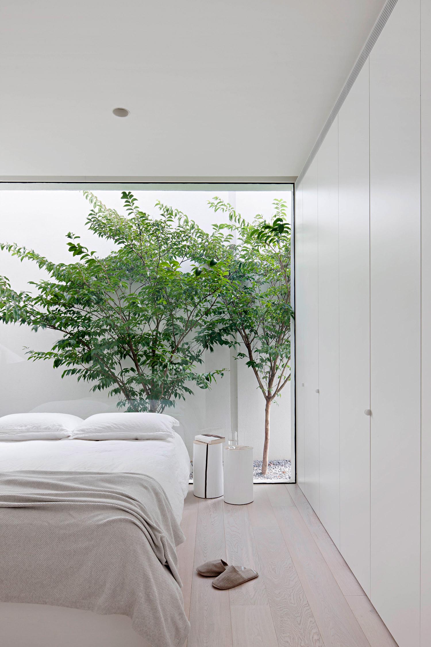 A modern bedroom with a neutral color palette, and a floor-to-ceiling window. 