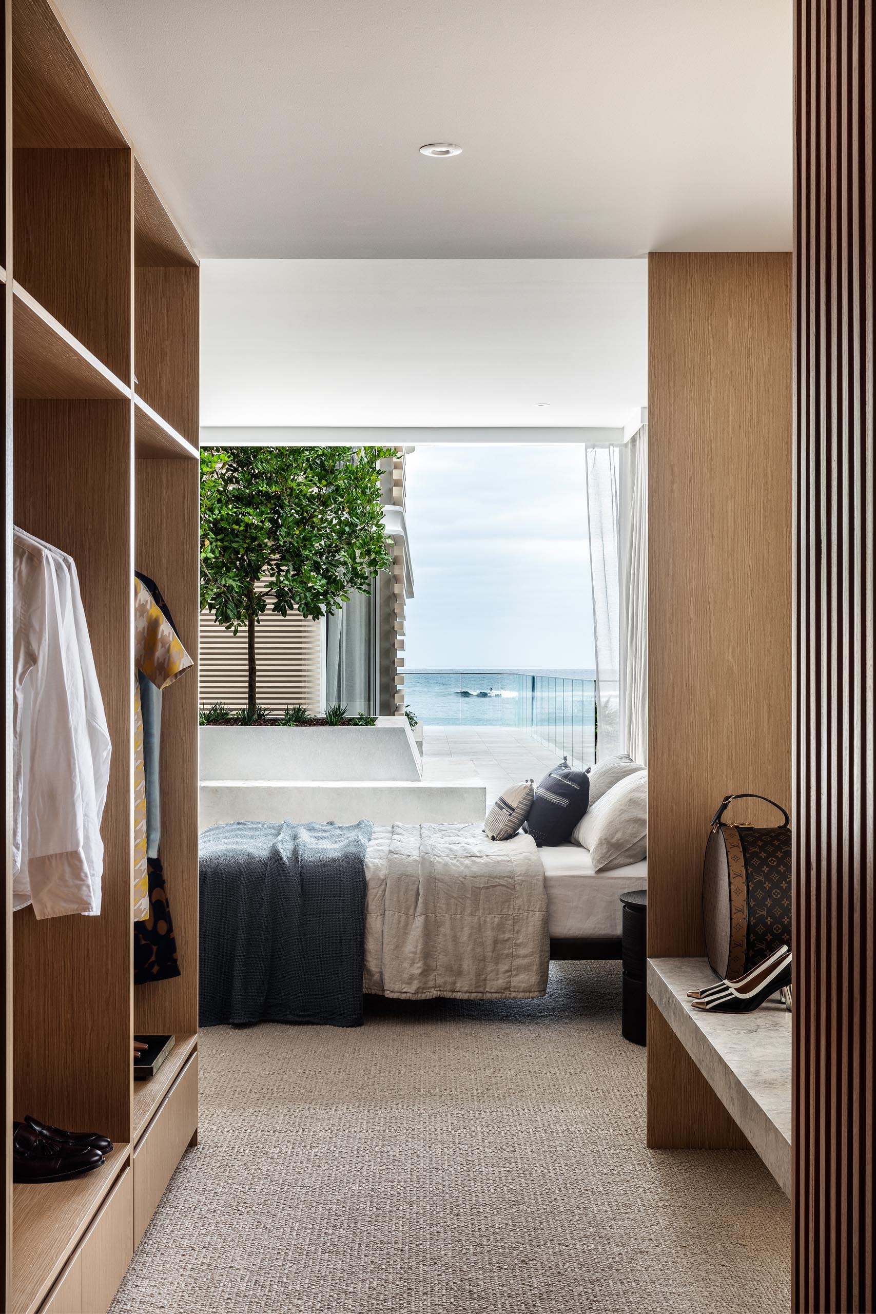 This modern walk-in closet has plenty of storage for clothes, and also includes a stone bench by the window.