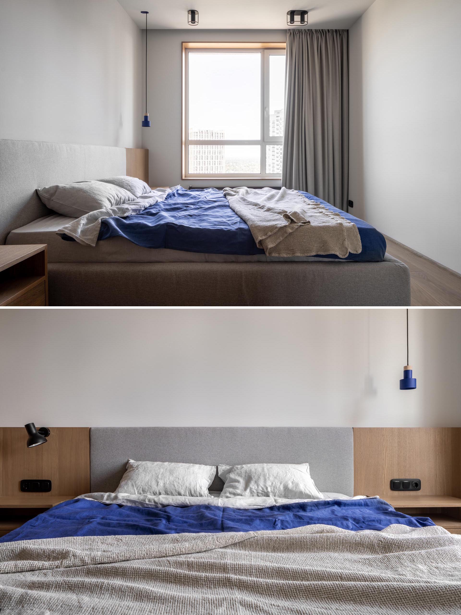 A modern bedroom with grey upholstered bed frame that's flanked by custom designed wood bedside tables, while floor-to-ceiling curtains cover the window.