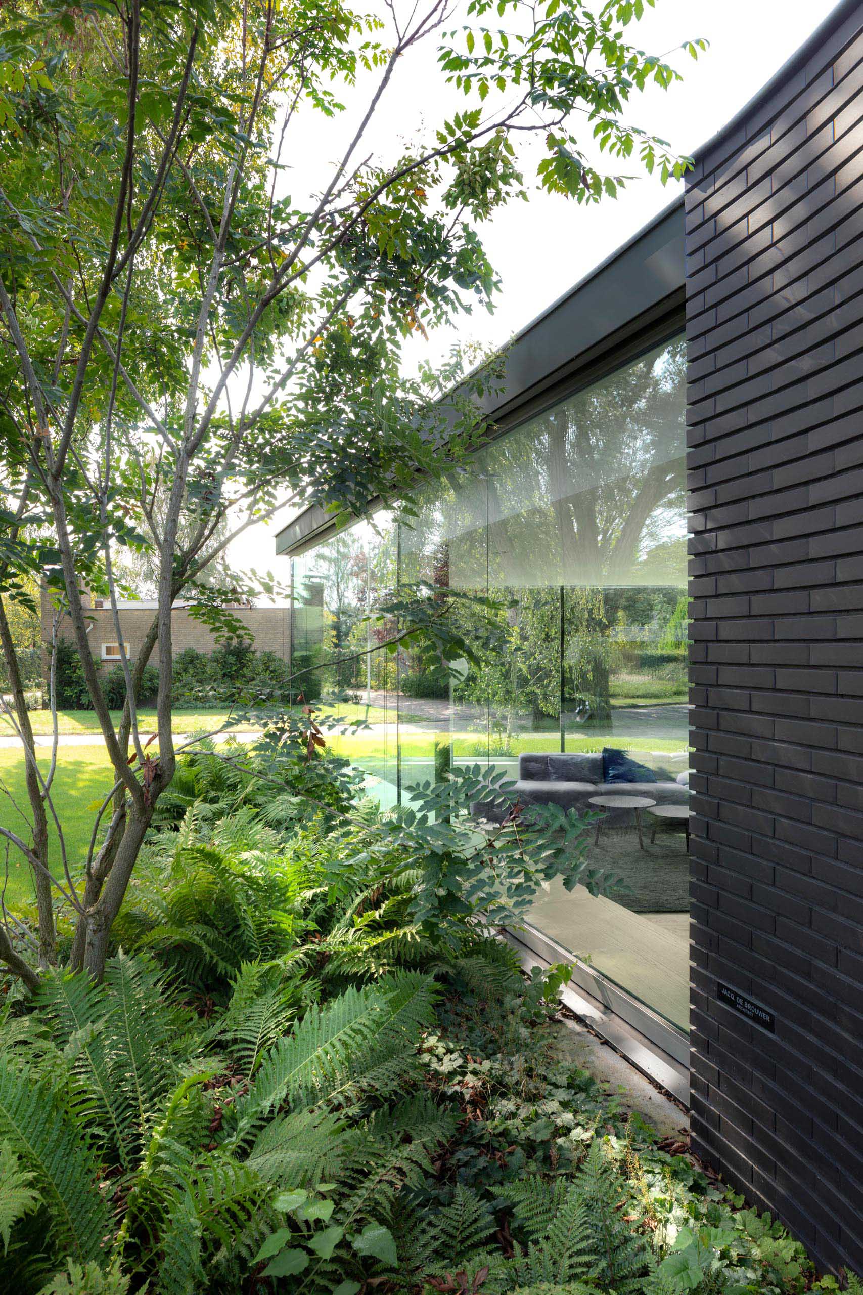 A modern home with a black brick exterior and large glass walls that fill the interior with an abundance of natural light.