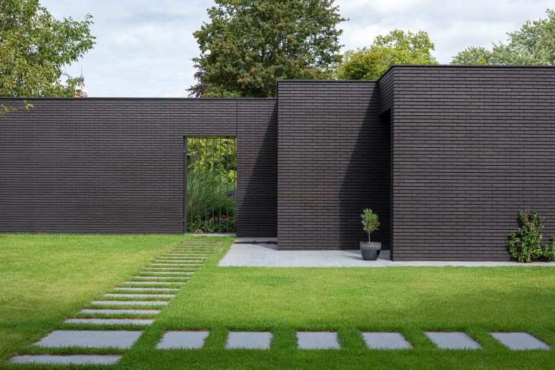 This Home Combines A Black Brick Exterior With Large Glass Walls For A