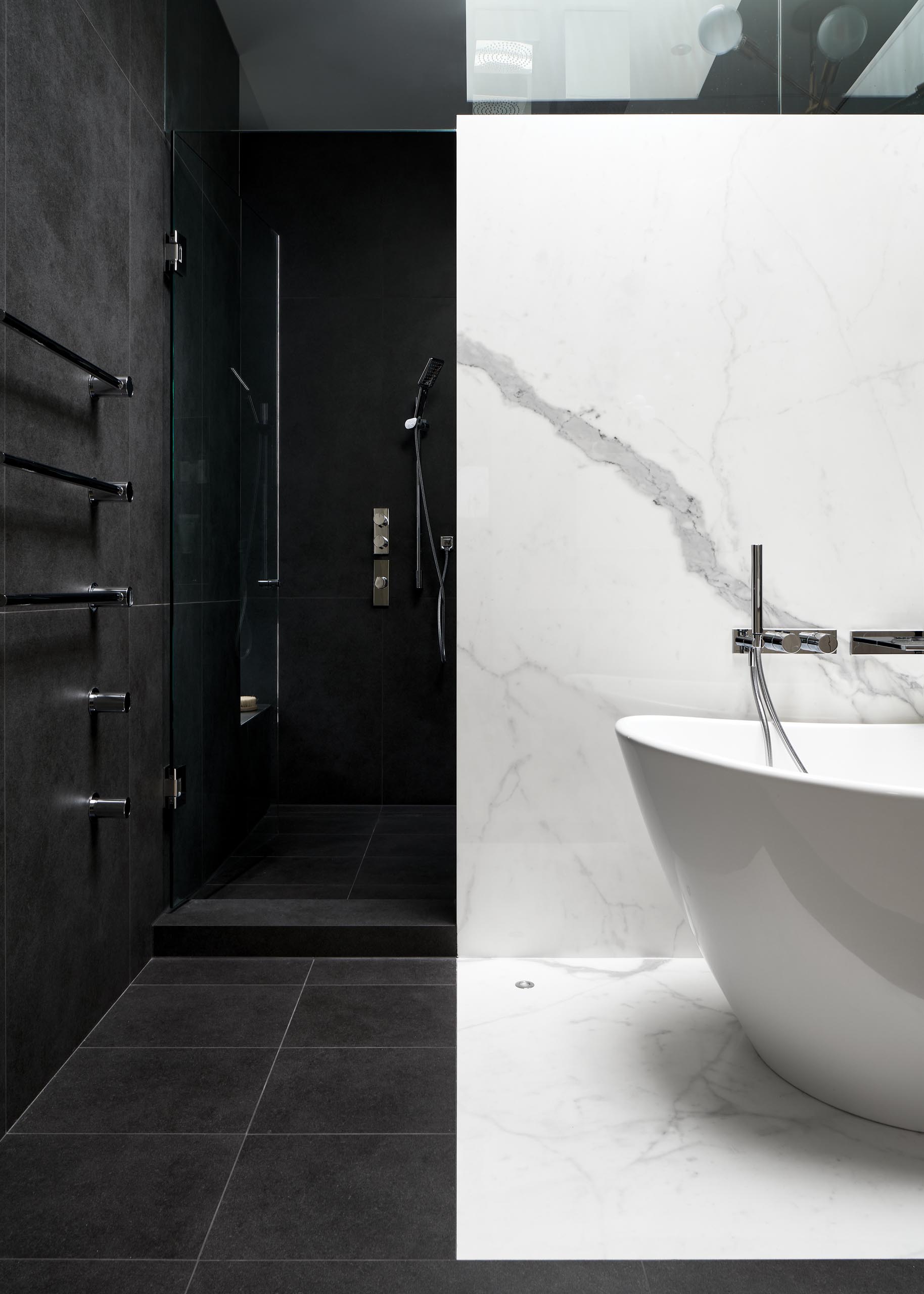 In this modern bathroom, white and black porcelain slabs are combined to create a dramatic contrast. 