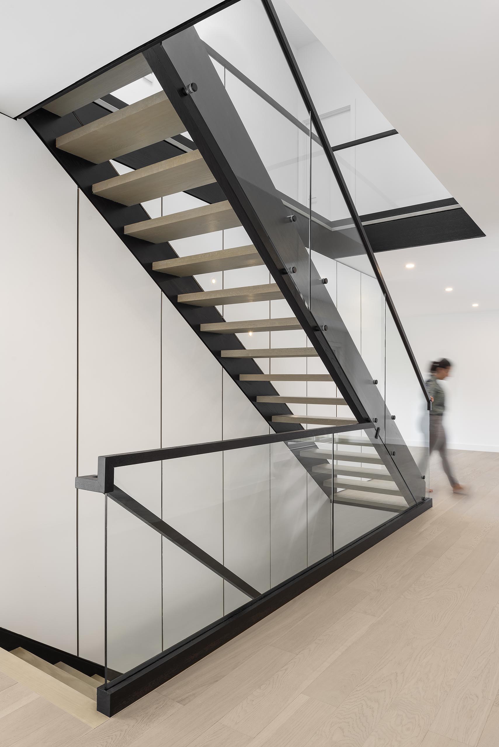 A modern staircase with a black steel support and floating light wood treads.