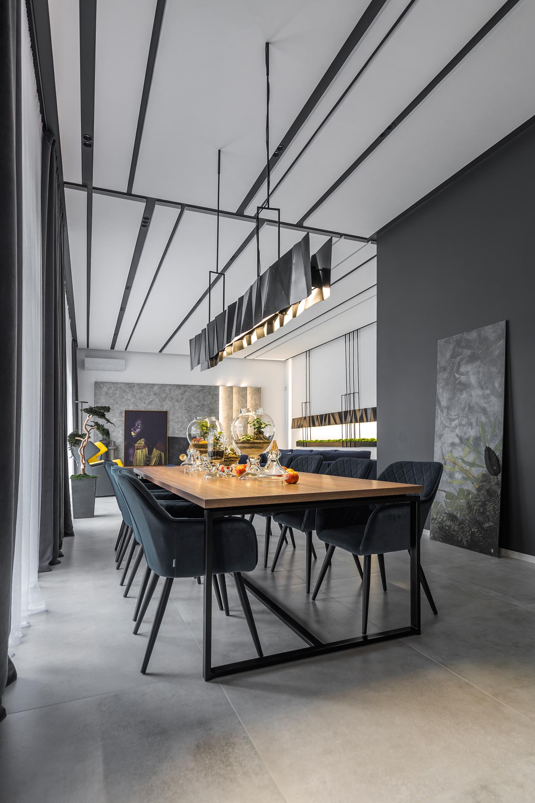 A modern dining room with wood table and a long matte black metal lighting fixture.