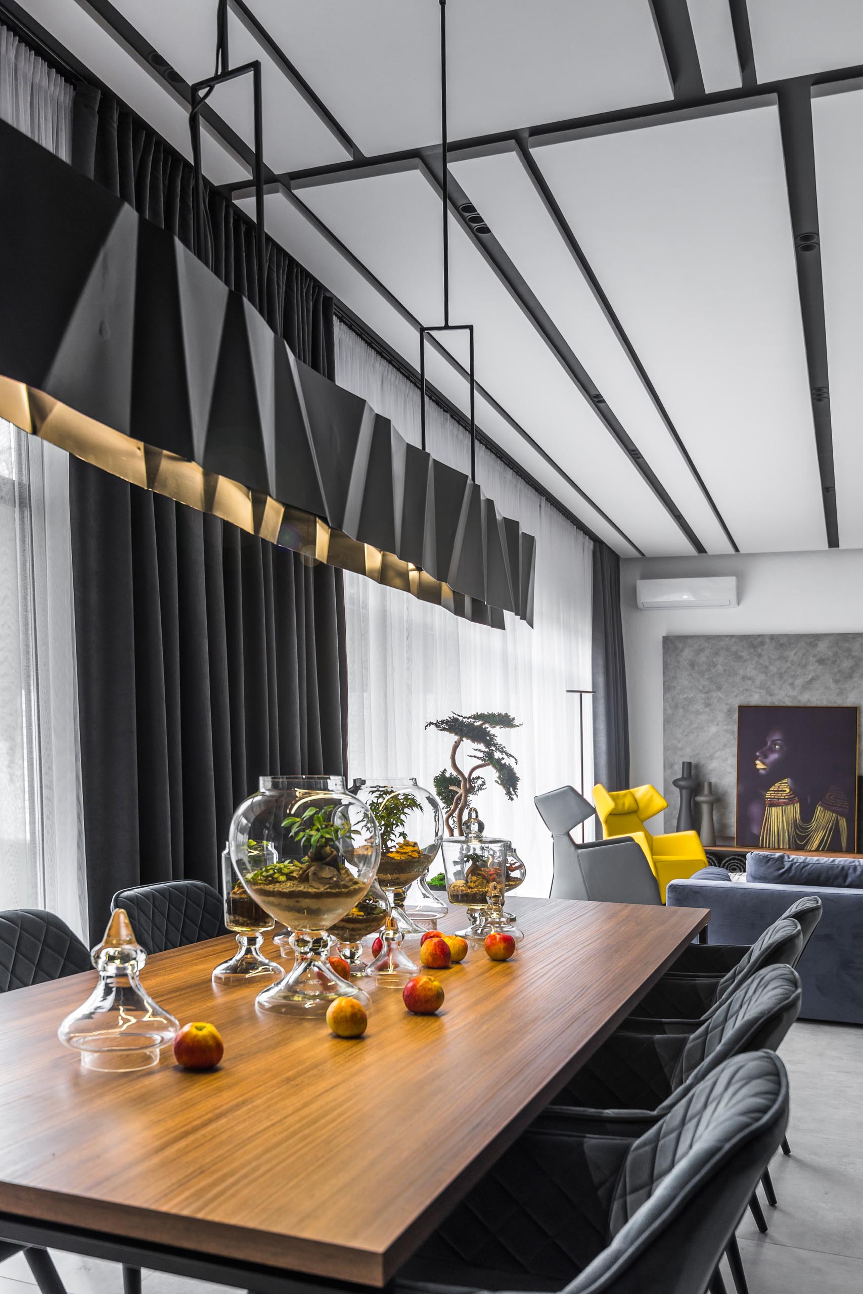 A modern dining room with a long matte black geometric metal lighting fixture.